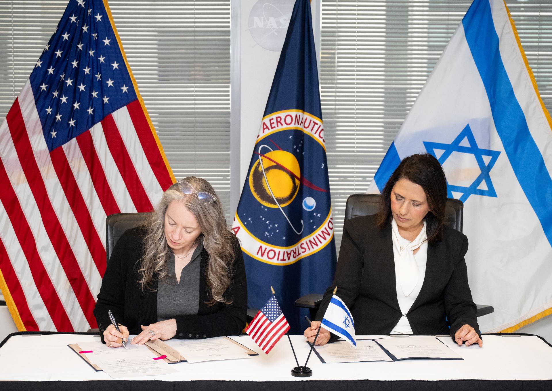 Meredith McKay, acting associate administrator for NASA’s Office of International and Interagency Relations, left, and Israel’s Minister for Innovation, Science, and Technology Gila Gamliel sign the US-Israel Space Cooperation Framework Agreement Extension, Wednesday, Dec. 10, 2025, at the Mary W. Jackson NASA Headquarters building in Washington. Photo Credit: (NASA/Joel Kowsky)