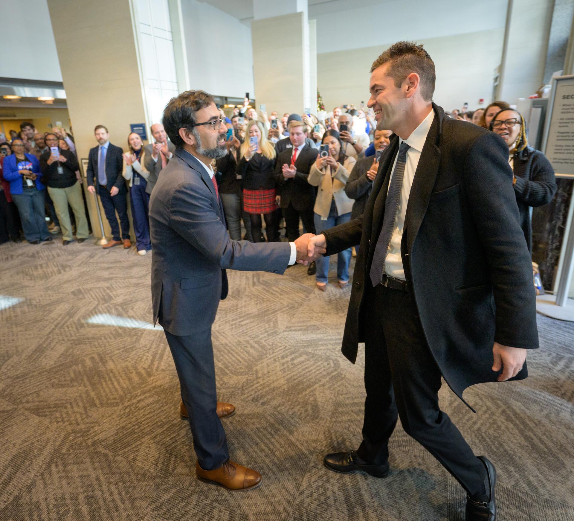 NASA Associate Administrator Amit Kshatriya, left, along with NASA employees, welcomes NASA Administrator Jared Isaacman to the Mary W. Jackson NASA Headquarters Building in Washington, Thursday, Dec. 18, 2025. Photo Credit: (NASA/Bill Ingalls)