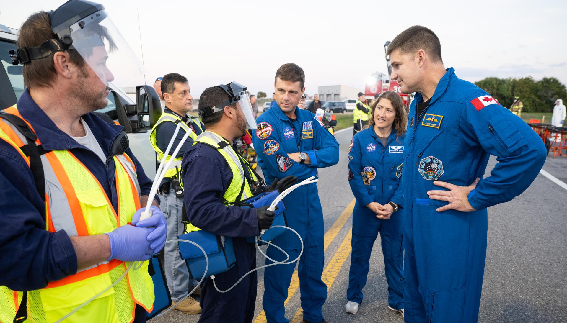 CSA (Canadian Space Agency) astronaut Jeremy Hansen, Artemis II mission specialist, right, and NASA astronauts Christina Koch, Artemis II mission specialist, and Reid Wiseman, Artemis II commander, talk with team members at NASA's Kennedy Space Center in Florida as they practiced various emergency rescue training scenarios with the Artemis II crew, Friday, Dec. 19, 2025, ahead of the Artemis II mission. In the unlikely event of an emergency during launch countdown at Launch Complex 39B, personnel will be transported in mine-resistant ambush protected vehicles, or MRAPS, from the pad and to one of the triage site locations at Kennedy. Photo Credit: (NASA/Joel Kowsky)