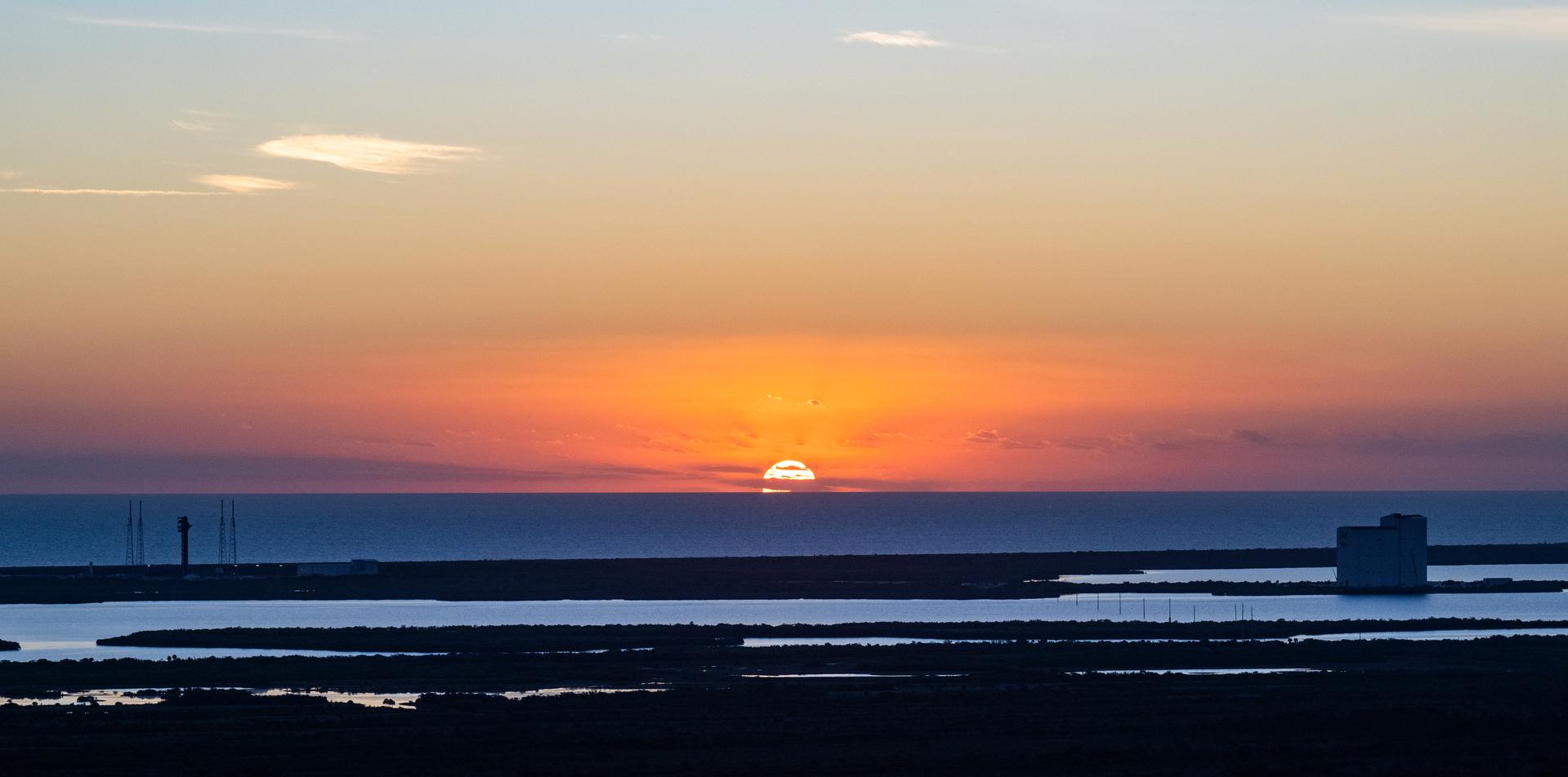 The sun rises shortly before Artemis II crewmembers NASA astronauts Reid Wiseman, commander; Victor Glover, pilot; Christina Koch, mission specialist; and CSA (Canadian Space Agency) astronaut Jeremy Hansen, mission specialist participate in the Artemis II countdown demonstration test, Saturday, Dec. 20, 2025, at NASA’s Kennedy Space Center in Florida. For this operation, the Artemis II crew and launch teams are simulating the launch day timeline including suit-up, walkout, and spacecraft ingress and egress. Through the Artemis campaign, NASA will send astronauts to explore the Moon for scientific discovery, economic benefits, and to build the foundation for the first crewed missions to Mars, for the benefit of all. Photo Credit: (NASA/Keegan Barber)