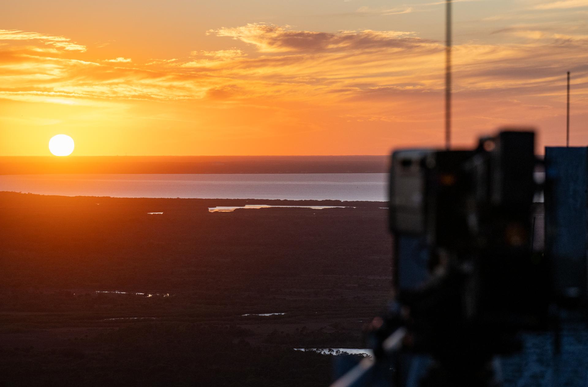 The sun sets as Artemis II crewmembers NASA astronauts Reid Wiseman, commander; Victor Glover, pilot; Christina Koch, mission specialist; and CSA (Canadian Space Agency) astronaut Jeremy Hansen, mission specialist participate in the Artemis II countdown demonstration test, Saturday, Dec. 20, 2025, at NASA’s Kennedy Space Center in Florida. For this operation, the Artemis II crew and launch teams are simulating the launch day timeline including suit-up, walkout, and spacecraft ingress and egress. Through the Artemis campaign, NASA will send astronauts to explore the Moon for scientific discovery, economic benefits, and to build the foundation for the first crewed missions to Mars, for the benefit of all. Photo Credit: (NASA/Keegan Barber)
