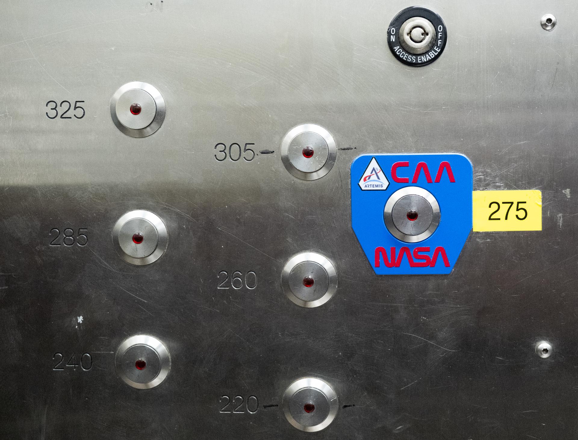 The elevator button for the 275-foot level of the mobile launcher is seen teams prepare for Artemis II crewmembers NASA astronauts Reid Wiseman, commander; Victor Glover, pilot; Christina Koch, mission specialist; and CSA (Canadian Space Agency) astronaut Jeremy Hansen, mission specialist; to arrive and board their Orion spacecraft atop NASA’s Space Launch System rocket during the Artemis II countdown demonstration test, Saturday, Dec. 20, 2025, inside the Vehicle Assembly Building at NASA’s Kennedy Space Center in Florida. For this operation, the Artemis II crew and launch teams are simulating the launch day timeline including suit-up, walkout, and spacecraft ingress and egress. Through the Artemis campaign, NASA will send astronauts to explore the Moon for scientific discovery, economic benefits, and to build the foundation for the first crewed missions to Mars, for the benefit of all. Photo Credit: (NASA/Joel Kowsky)