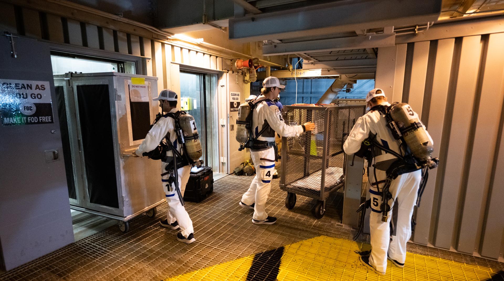 Taylor Hose, left, Christian Warriner, center, and Will Sattler of the Closeout Crew are seen as they prepare for the arrival of Artemis II crewmembers NASA astronauts Reid Wiseman, commander; Victor Glover, pilot; Christina Koch, mission specialist; and CSA (Canadian Space Agency) astronaut Jeremy Hansen, mission specialist; at the 275-foot level of the mobile launcher to board their Orion spacecraft atop NASA’s Space Launch System rocket during the Artemis II countdown demonstration test, Saturday, Dec. 20, 2025, inside the Vehicle Assembly Building at NASA’s Kennedy Space Center in Florida. For this operation, the Artemis II crew and launch teams are simulating the launch day timeline including suit-up, walkout, and spacecraft ingress and egress.  Through the Artemis campaign, NASA will send astronauts to explore the Moon for scientific discovery, economic benefits, and to build the foundation for the first crewed missions to Mars, for the benefit of all. Photo Credit: (NASA/Joel Kowsky)