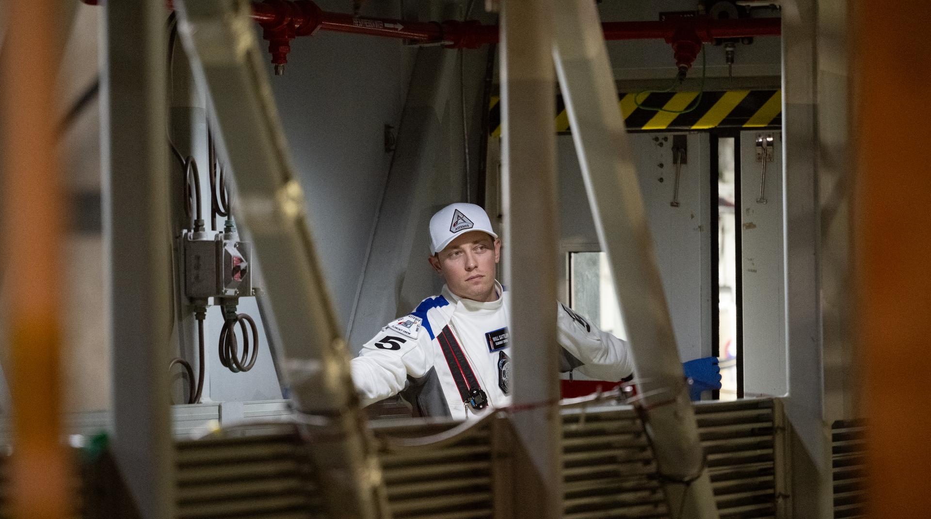 Will Sattler of the Closeout Crew is seen on the crew access arm just outside of the white room awaiting the arrival of Artemis II crewmembers NASA astronauts Reid Wiseman, commander; Victor Glover, pilot; Christina Koch, mission specialist; and CSA (Canadian Space Agency) astronaut Jeremy Hansen, mission specialist; at the 275-foot level of the mobile launcher as they prepare to board their Orion spacecraft atop NASA’s Space Launch System rocket during the Artemis II countdown demonstration test, Saturday, Dec. 20, 2025, inside the Vehicle Assembly Building at NASA’s Kennedy Space Center in Florida. For this operation, the Artemis II crew and launch teams are simulating the launch day timeline including suit-up, walkout, and spacecraft ingress and egress. Through the Artemis campaign, NASA will send astronauts to explore the Moon for scientific discovery, economic benefits, and to build the foundation for the first crewed missions to Mars, for the benefit of all. Photo Credit: (NASA/Joel Kowsky)