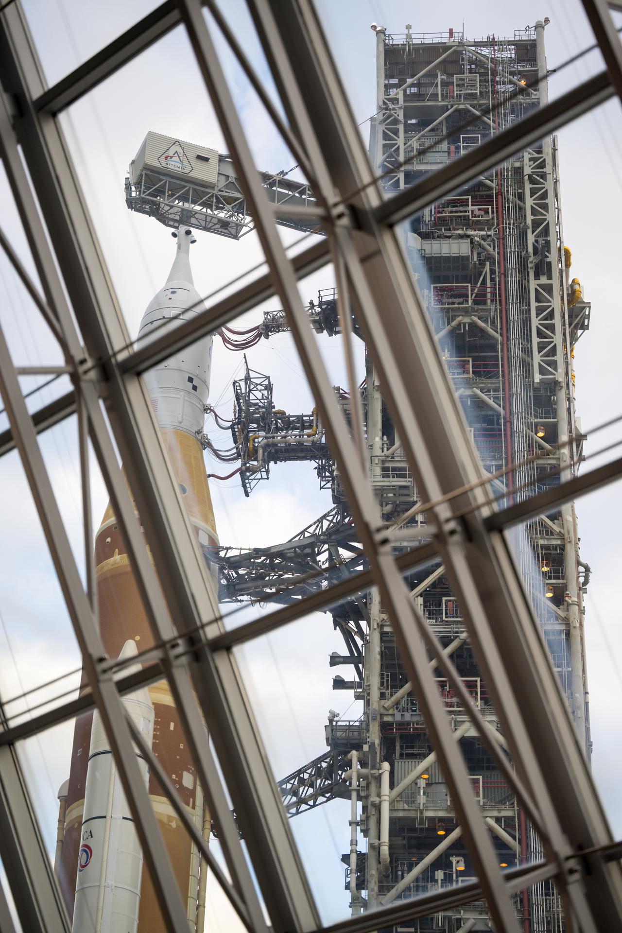NASA’s Artemis II Space Launch System (SLS) rocket and Orion spacecraft, secured to the mobile launcher, is seen through the windows of Firing Room One of the Rocco A. Petrone Launch Control Center as it rolls out of High Bay 3 of the Vehicle Assembly Building to Launch Complex 39B, Saturday, Jan. 17, 2026, at NASA’s Kennedy Space Center in Florida. NASA’s Artemis II test flight will take Commander Reid Wiseman, Pilot Victor Glover, and Mission Specialist Christina Koch from NASA, and Mission Specialist Jeremy Hansen from the CSA (Canadian Space Agency), around the Moon and back to Earth no later than no later than April 2026. Photo Credit: (NASA/Aubrey Gemignani)