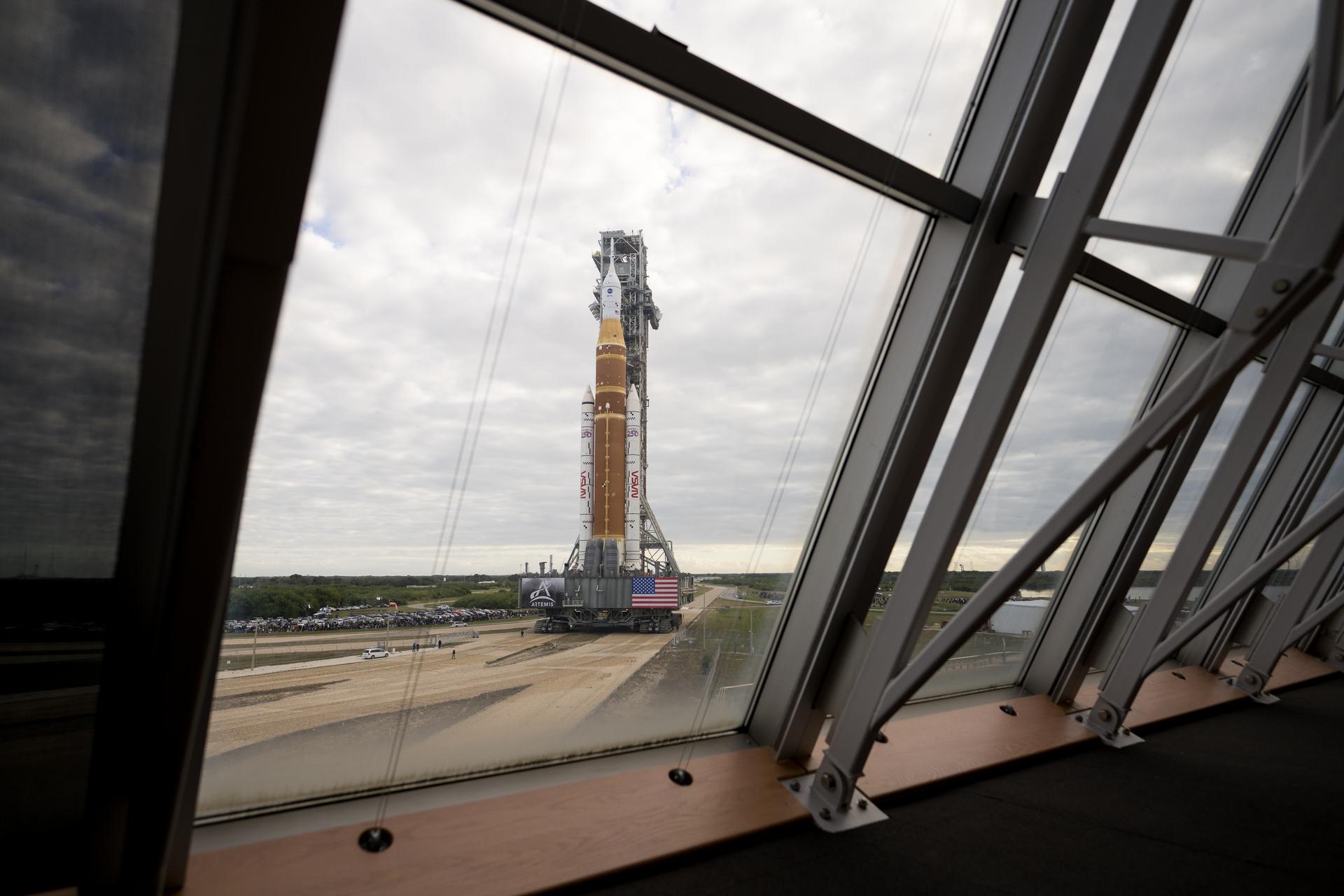 NASA’s Artemis II Space Launch System (SLS) rocket and Orion spacecraft, secured to the mobile launcher, is seen through the windows of Firing Room One of the Rocco A. Petrone Launch Control Center as it rolls out of High Bay 3 of the Vehicle Assembly Building to Launch Complex 39B, Saturday, Jan. 17, 2026, at NASA’s Kennedy Space Center in Florida. NASA’s Artemis II test flight will take Commander Reid Wiseman, Pilot Victor Glover, and Mission Specialist Christina Koch from NASA, and Mission Specialist Jeremy Hansen from the CSA (Canadian Space Agency), around the Moon and back to Earth no later than April 2026. Photo Credit: (NASA/Aubrey Gemignani)