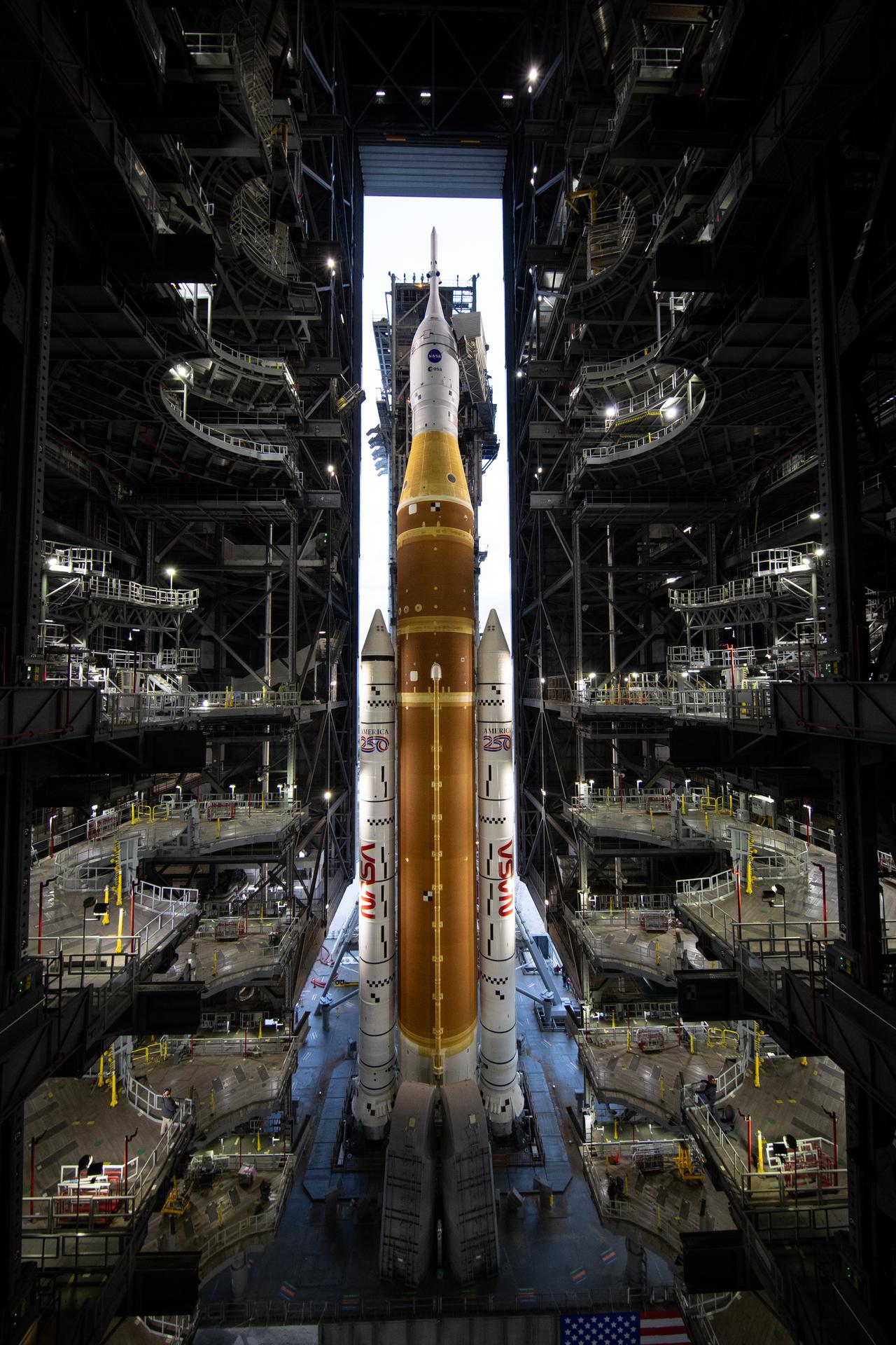 NASA’s Space Launch System (SLS) rocket and Orion spacecraft, secured to the mobile launcher, is seen as it rolls out of the Vehicle Assembly Building to Launch Pad 39B, Saturday, Jan. 17, 2026, at NASA’s Kennedy Space Center in Florida. NASA’s Artemis II test flight will take Commander Reid Wiseman, Pilot Victor Glover, and Mission Specialist Christina Koch from NASA, and Mission Specialist Jeremy Hansen from the CSA (Canadian Space Agency), around the Moon and back to Earth no later than April 2026. Photo Credit: (NASA/Joel Kowsky)