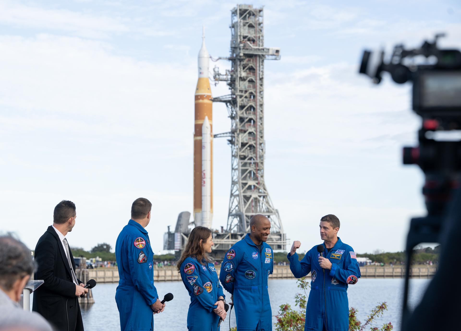 NASA astronaut Reid Wiseman, Artemis II commander, right, speaks to members of the media alongside NASA Administrator Jared Isaacman, left, CSA (Canadian Space Agency) astronaut Jeremy Hansen, Artemis II mission specialist, NASA astronaut Christina Koch, Artemis II mission specialist, and NASA astronaut Victor Glover, Artemis II pilot, as NASA’s Artemis II SLS (Space Launch System) rocket and Orion spacecraft rolls out to Launch Complex 39B at NASA’s Kennedy Space Center in Florida on Saturday, Jan. 17, 2026. In the coming weeks, engineers will prepare for the wet dress rehearsal, a two-day test that simulates launch day. The Artemis II test flight will take Commander Reid Wiseman, Pilot Victor Glover, and Mission Specialist Christina Koch from NASA, and Mission Specialist Jeremy Hansen from the CSA (Canadian Space Agency), around the Moon and back to Earth no later than April 2026. Photo Credit: (NASA/Joel Kowsky)