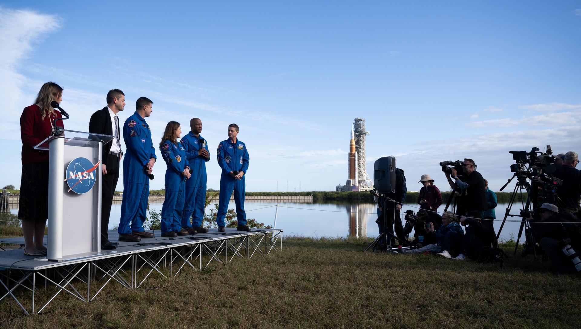 NASA astronaut Victor Glover, Artemis II pilot, second from right, speaks to members of the media alongside NASA press secretary Bethany Stevens, left, NASA Administrator Jared Isaacman, CSA (Canadian Space Agency) astronaut Jeremy Hansen, Artemis II mission specialist, NASA astronaut Christina Koch, Artemis II mission specialist, and NASA astronaut Reid Wiseman, Artemis II commander, as NASA’s Artemis II SLS (Space Launch System) rocket and Orion spacecraft rolls out to Launch Complex 39B at NASA’s Kennedy Space Center in Florida on Saturday, Jan. 17, 2026. In the coming weeks, engineers will prepare for the wet dress rehearsal, a two-day test that simulates launch day. The Artemis II test flight will take Wiseman, Glover, Koch, and Hansen around the Moon and back to Earth no later than April 2026. Photo Credit: (NASA/Joel Kowsky)