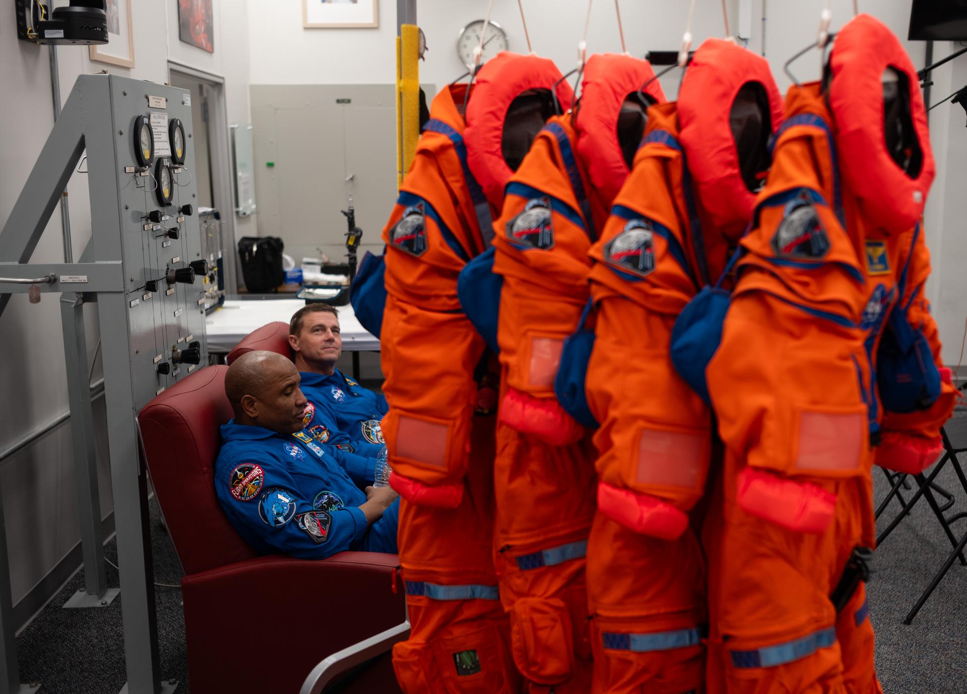 NASA astronaut Victor Glover, Artemis II pilot and NASA astronaut Reid Wiseman, Artemis II commander are seen alongside the Orion Crew Survival System suits that they and fellow crewmates NASA astronaut Christina Koch, Artemis II mission specialist and CSA (Canadian Space Agency) astronaut Jeremy Hansen, Artemis II mission specialist, as they wait to participate in an interview in the suit-up room of the Neil A. Armstrong Operations and Checkout Building, Saturday, Jan. 17, 2026, at NASA’s Kennedy Space Center in Florida. NASA’s Artemis II test flight will take Glover, Wiseman, Koch, and Hansen around the Moon and back to Earth no later than April 2026. Photo Credit: (NASA/Joel Kowsky)