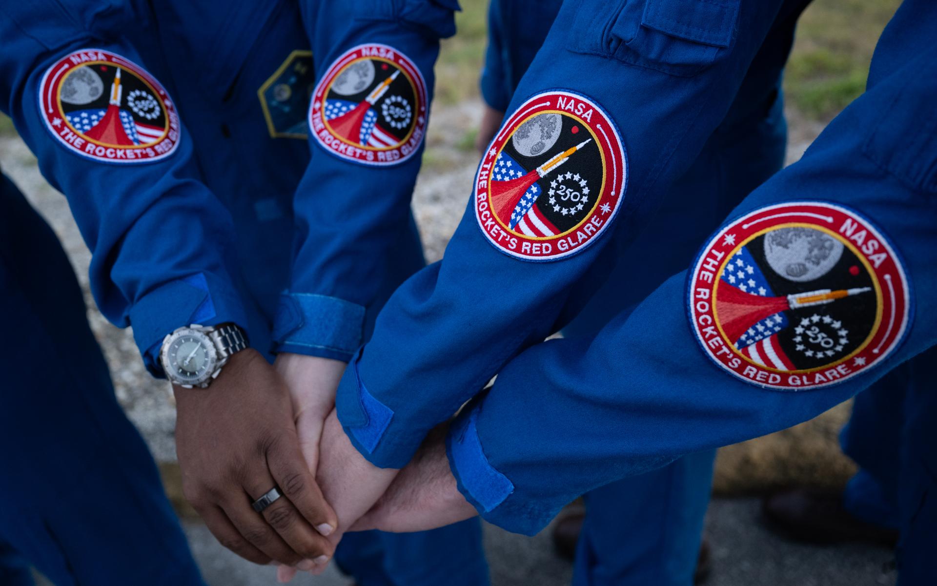 NASA astronauts Victor Glover, Artemis II pilot, left, Christina Koch, Artemis II mission specialist, Reid Wiseman, Artemis II commander, and CSA (Canadian Space Agency) astronaut Jeremy Hansen, Artemis II mission specialist, pose for a picture showing the Freedom 250 Commemorative Patch on their flight suits,  Saturday, Jan. 17, 2026, at NASA’s Kennedy Space Center in Florida. The patch honors America’s 250th anniversary of declaring independence, establishing a sovereign nation. The theme of NASA’s celebration is “Rocket’s Red Glare” which references the iconic lyric within the Star-Spangled Banner, our national anthem. NASA’s Artemis II test flight will take Glover, Koch, Wiseman, and Hansen around the Moon and back to Earth no later than April 2026. Photo Credit: (NASA/Joel Kowsky)