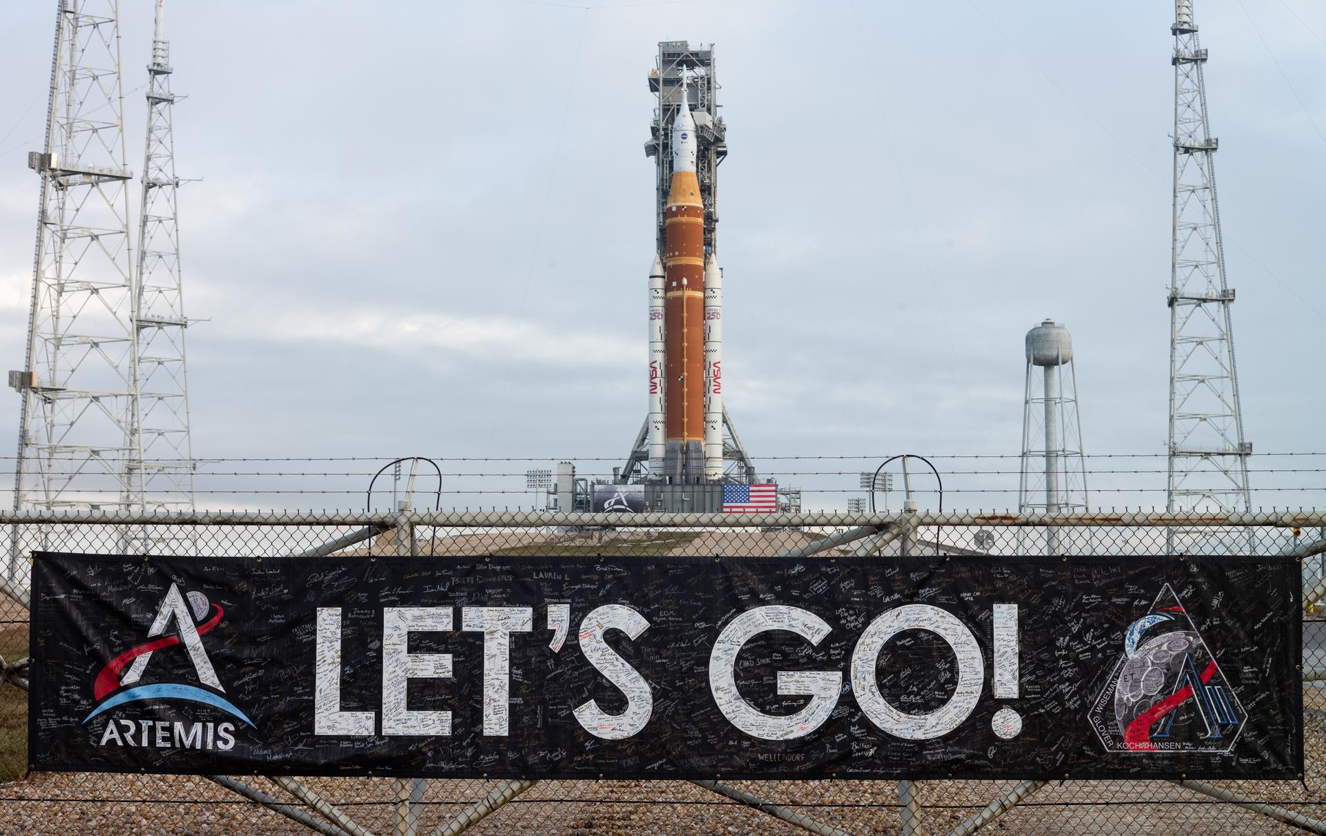 A banner covered with the signatures of NASA employees and contractors is seen on the perimeter fence of Launch Complex 39B after NASA’s Artemis II Space Launch System (SLS) rocket and Orion spacecraft were rolled out to the launch pad, Sunday, Jan. 18, 2026, at NASA’s Kennedy Space Center in Florida. NASA’s Artemis II test flight will take Commander Reid Wiseman, Pilot Victor Glover, and Mission Specialist Christina Koch from NASA, and Mission Specialist Jeremy Hansen from the CSA (Canadian Space Agency), around the Moon and back to Earth no later than April 2026. Photo Credit: (NASA/Joel Kowsky)