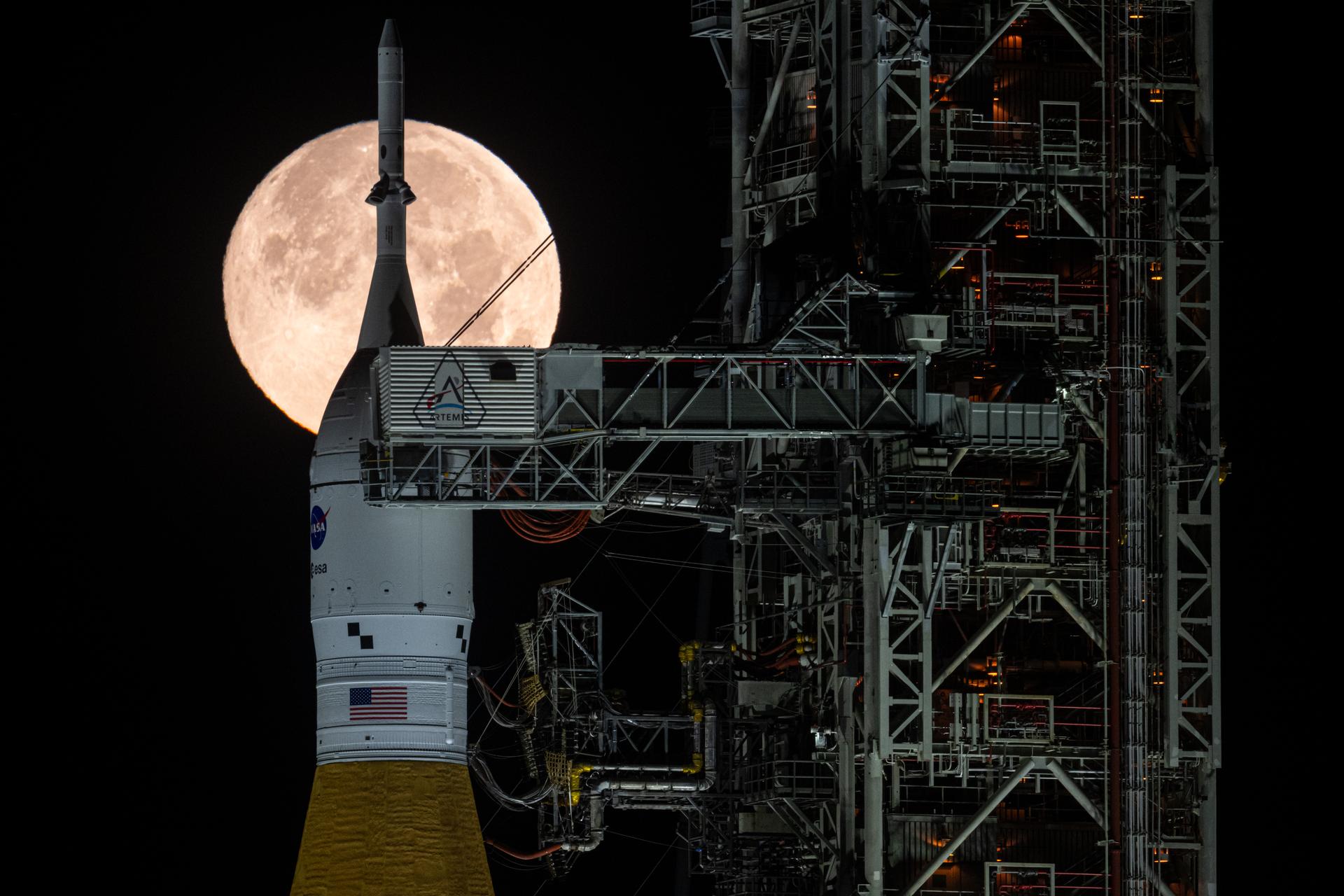 The full Moon is seen behind NASA’s Artemis II Space Launch System (SLS) rocket and Orion spacecraft, standing atop a mobile launcher at Launch Complex 39B, Sunday, Feb. 1, 2026, at NASA’s Kennedy Space Center in Florida. NASA’s Artemis II test flight will take Commander Reid Wiseman, Pilot Victor Glover, and Mission Specialist Christina Koch from NASA, and Mission Specialist Jeremy Hansen from the CSA (Canadian Space Agency), around the Moon and back to Earth no later than April 2026. Photo Credit: (NASA/John Kraus)