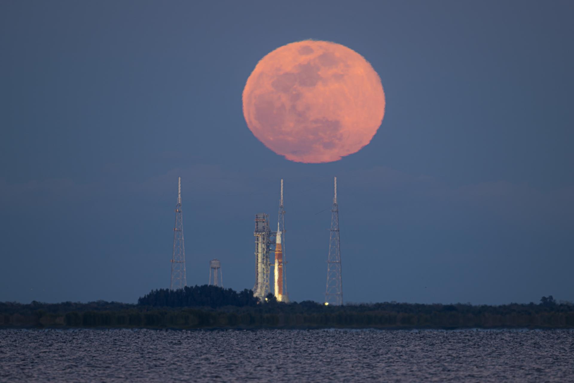 The full Moon rises behind NASA’s Artemis II Space Launch System (SLS) rocket and Orion spacecraft, standing atop a mobile launcher at Launch Complex 39B, Sunday, Feb. 1, 2026, at NASA’s Kennedy Space Center, as seen from Titusville, Fla. NASA’s Artemis II test flight will take Commander Reid Wiseman, Pilot Victor Glover, and Mission Specialist Christina Koch from NASA, and Mission Specialist Jeremy Hansen from the CSA (Canadian Space Agency), around the Moon and back to Earth no later than April 2026. Photo Credit: (NASA/John Kraus)