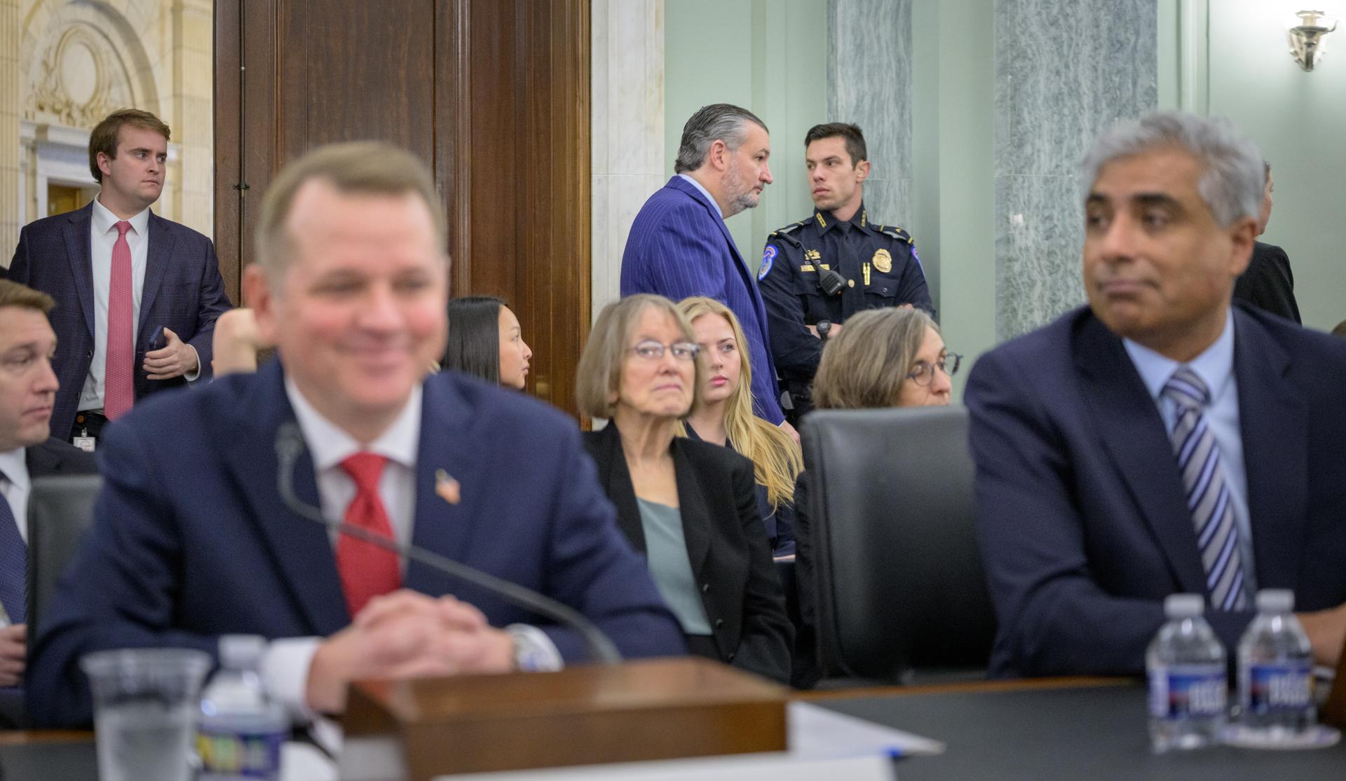 Sen. Ted Cruz, R-Texas, Chairman of the Senate Committee on Commerce, Science, and Transportation, background, walks into the confirmation hearing for Matthew Anderson, foreground left, President Trumps' nominee to be Deputy Administrator of the National Aeronautics and Space Administration, and Arvind Raman, President Trumps' nominee to be Under Secretary of Commerce for Standards and Technology and Director of the National Institute of Standards and Technology, foreground right, Thursday, March 5, 2026, at the Russell Senate Office Building in Washington. Photo Credit: (NASA/Bill Ingalls)
