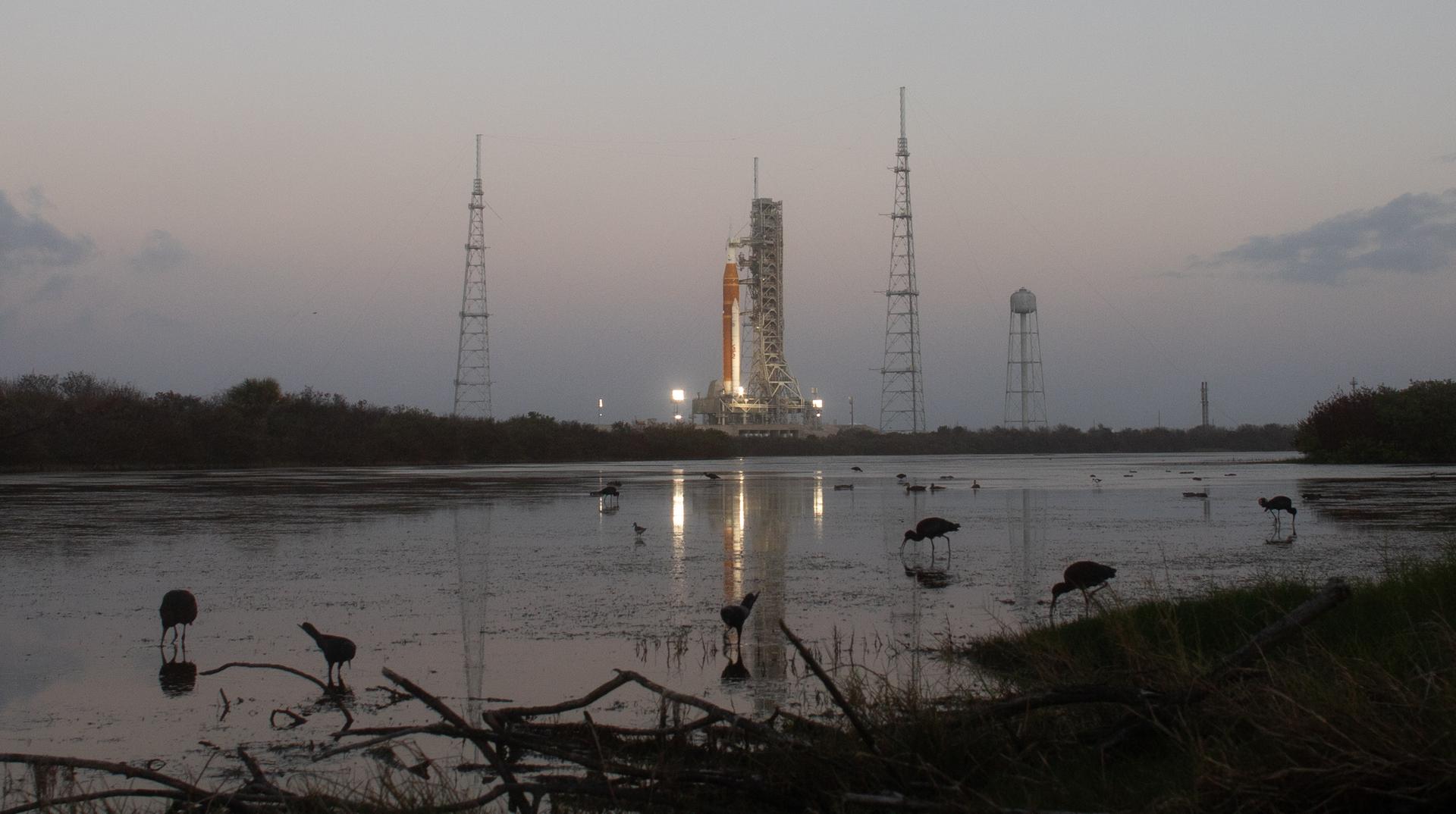 NASA’s Artemis II Space Launch System (SLS) rocket and Orion spacecraft are seen at sunrise atop a mobile launcher at Launch Complex 39B, Monday, March 30, 2026, as preparations for launch continue at NASA’s Kennedy Space Center in Florida. NASA’s Artemis II test flight will take Commander Reid Wiseman, Pilot Victor Glover, and Mission Specialist Christina Koch from NASA, and Mission Specialist Jeremy Hansen from the CSA (Canadian Space Agency), around the Moon and back to Earth with launch opportunities beginning in April 2026. Photo Credit: (NASA/Bill Ingalls)
