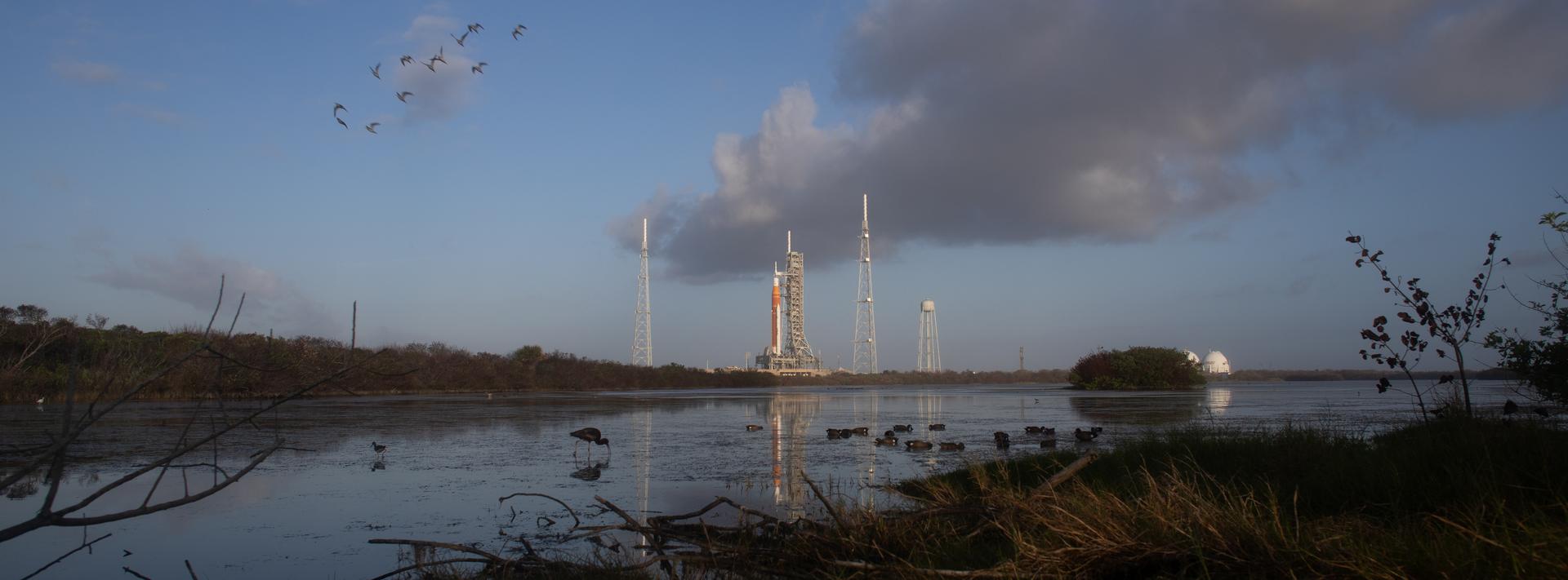 NASA’s Artemis II Space Launch System (SLS) rocket and Orion spacecraft are seen at sunrise atop a mobile launcher at Launch Complex 39B, Monday, March 30, 2026, as preparations for launch continue at NASA’s Kennedy Space Center in Florida. NASA’s Artemis II test flight will take Commander Reid Wiseman, Pilot Victor Glover, and Mission Specialist Christina Koch from NASA, and Mission Specialist Jeremy Hansen from the CSA (Canadian Space Agency), around the Moon and back to Earth with launch opportunities beginning in April 2026. Photo Credit: (NASA/Bill Ingalls)