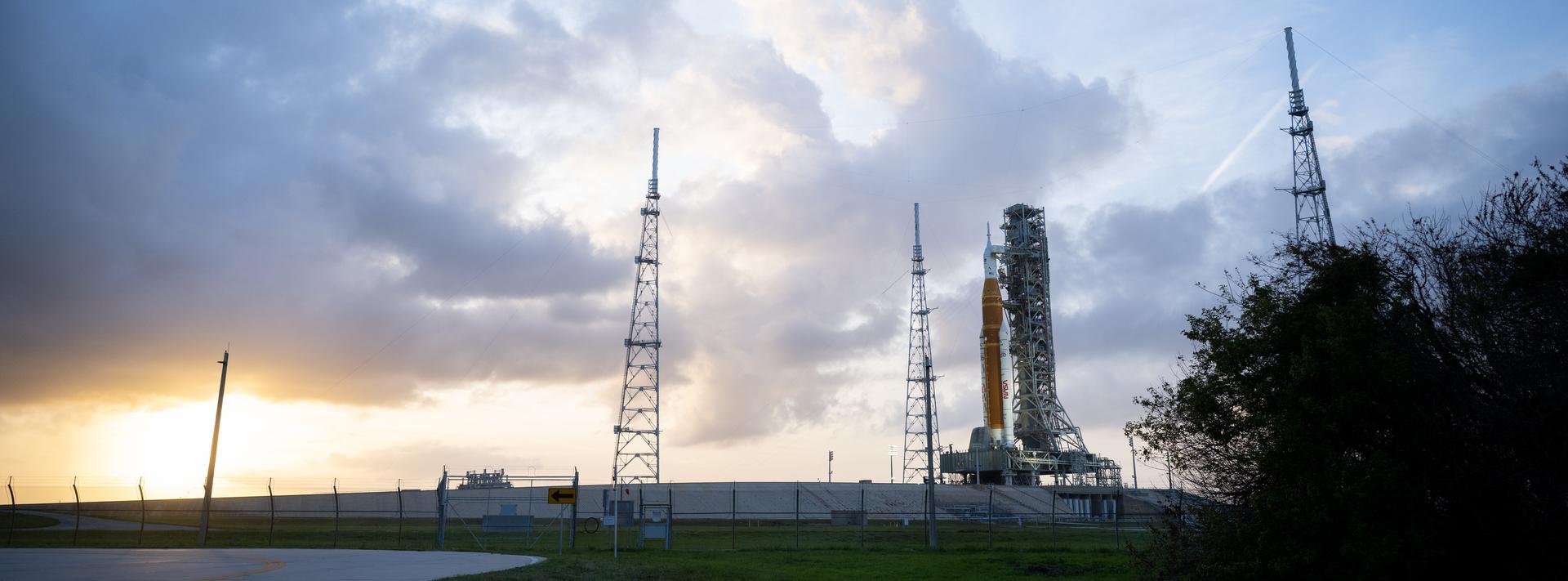 NASA’s Artemis II Space Launch System (SLS) rocket and Orion spacecraft are seen at sunset atop a mobile launcher at Launch Complex 39B, Monday, March 30, 2026, as preparations continue for launch at NASA’s Kennedy Space Center in Florida. NASA’s Artemis II test flight will take Commander Reid Wiseman, Pilot Victor Glover, and Mission Specialist Christina Koch from NASA, and Mission Specialist Jeremy Hansen from the CSA (Canadian Space Agency), around the Moon and back to Earth no later than no later than April 2026. Photo Credit: (NASA/Joel Kowsky)