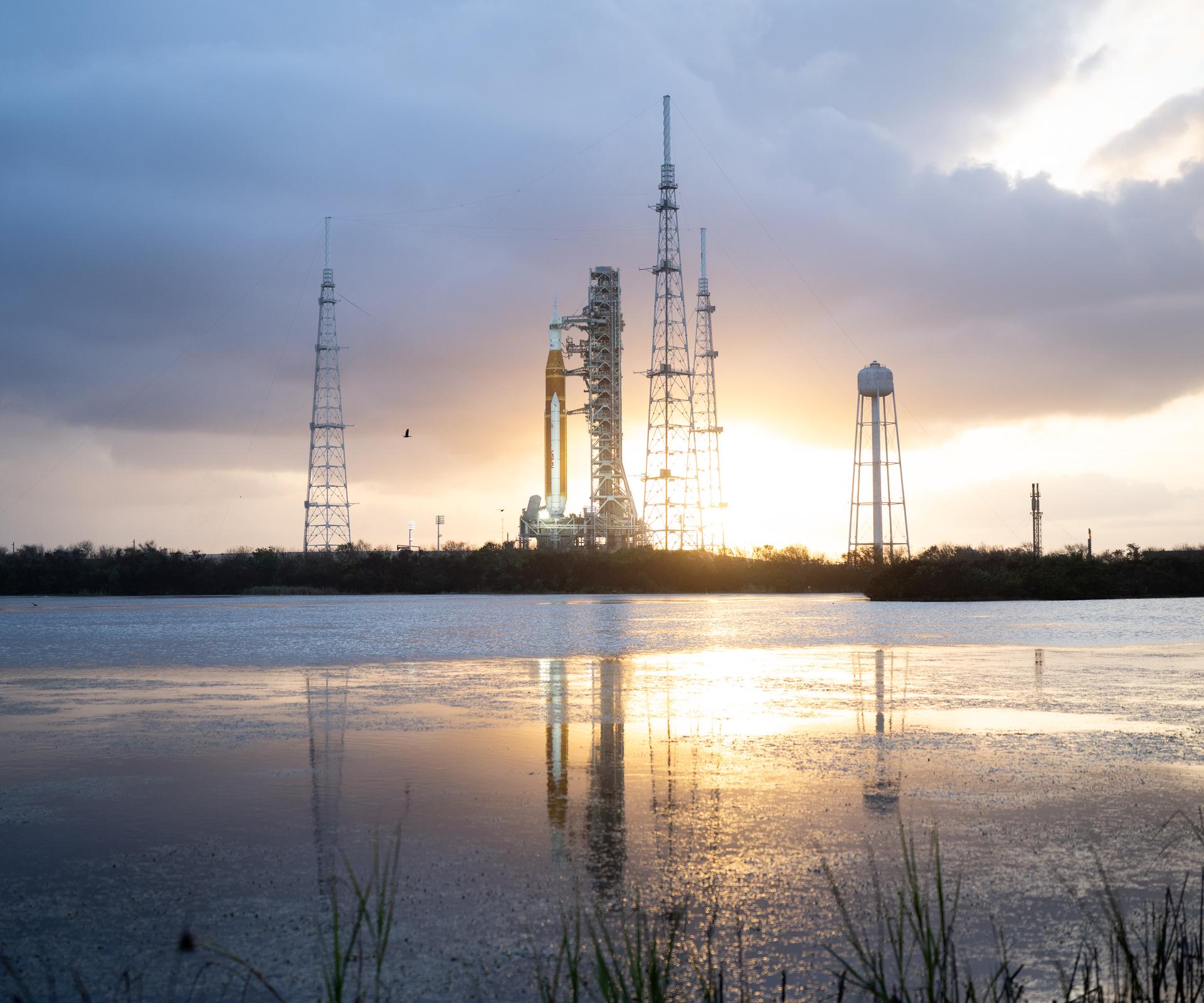 NASA’s Artemis II Space Launch System (SLS) rocket and Orion spacecraft are seen at sunset atop a mobile launcher at Launch Complex 39B, Monday, March 30, 2026, as preparations continue for launch at NASA’s Kennedy Space Center in Florida. NASA’s Artemis II test flight will take Commander Reid Wiseman, Pilot Victor Glover, and Mission Specialist Christina Koch from NASA, and Mission Specialist Jeremy Hansen from the CSA (Canadian Space Agency), around the Moon and back to Earth no later than no later than April 2026. Photo Credit: (NASA/Joel Kowsky)