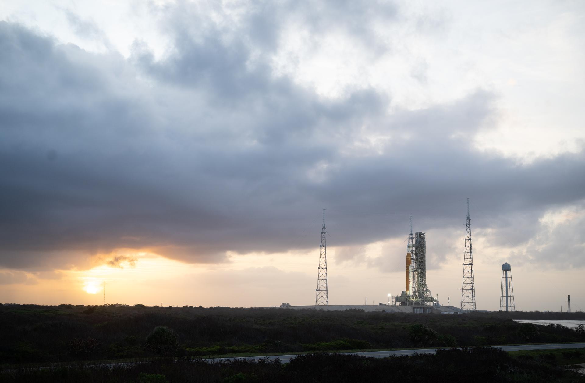NASA’s Artemis II Space Launch System (SLS) rocket and Orion spacecraft are seen at sunset atop a mobile launcher at Launch Complex 39B, Monday, March 30, 2026, as preparations continue for launch at NASA’s Kennedy Space Center in Florida. NASA’s Artemis II test flight will take Commander Reid Wiseman, Pilot Victor Glover, and Mission Specialist Christina Koch from NASA, and Mission Specialist Jeremy Hansen from the CSA (Canadian Space Agency), around the Moon and back to Earth no later than no later than April 2026. Photo Credit: (NASA/Joel Kowsky)