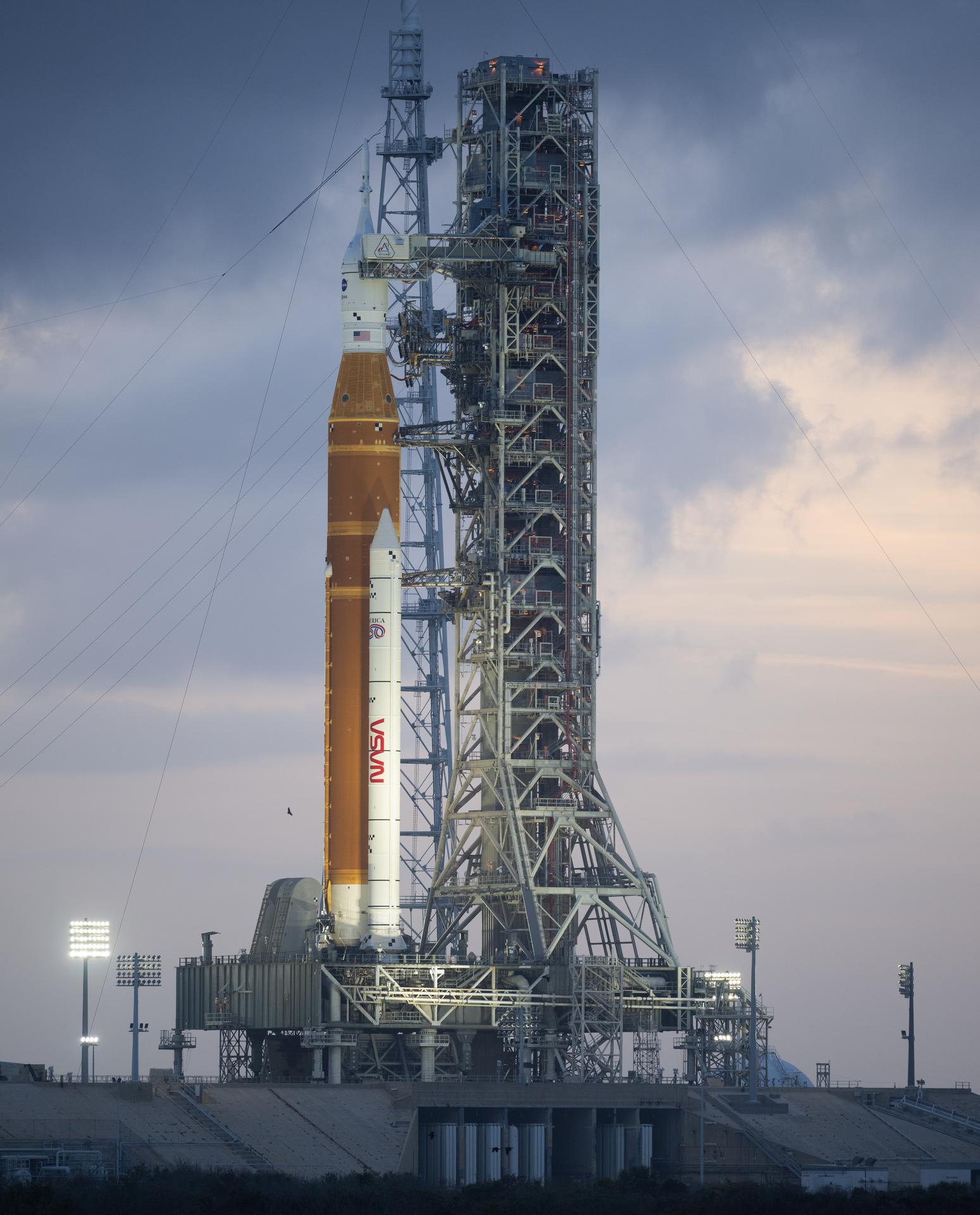 NASA’s Artemis II Space Launch System (SLS) rocket and Orion spacecraft are seen at sunset atop a mobile launcher at Launch Complex 39B, Monday, March 30, 2026, as preparations continue for launch at NASA’s Kennedy Space Center in Florida. NASA’s Artemis II test flight will take Commander Reid Wiseman, Pilot Victor Glover, and Mission Specialist Christina Koch from NASA, and Mission Specialist Jeremy Hansen from the CSA (Canadian Space Agency), around the Moon and back to Earth no later than no later than April 2026. Photo Credit: (NASA/Joel Kowsky)