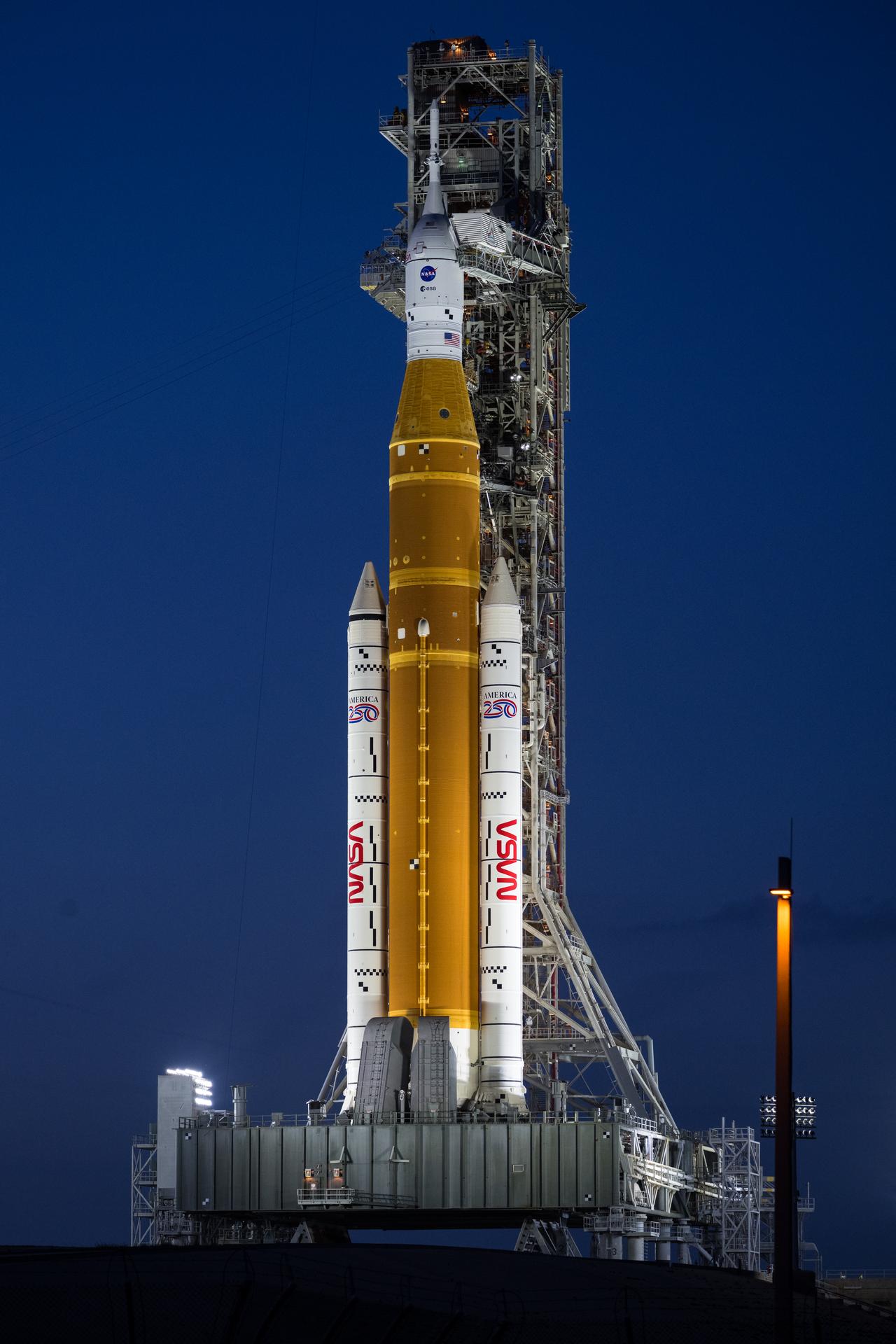 NASA’s Artemis II Space Launch System (SLS) rocket and Orion spacecraft are seen at sunset at Launch Complex 39B, Tuesday, March 31, 2026, at NASA’s Kennedy Space Center in Florida. The Artemis II test flight will take Commander Reid Wiseman, Pilot Victor Glover, and Mission Specialist Christina Koch from NASA, and Mission Specialist Jeremy Hansen from the CSA (Canadian Space Agency), around the Moon and back to Earth with launch opportunities beginning in April 2026. Photo Credit: (NASA/Aubrey Gemignani)