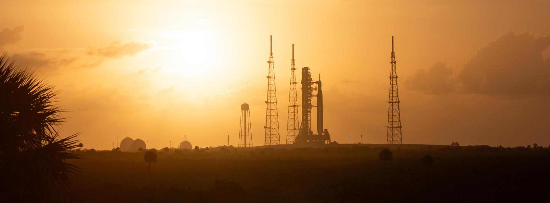 NASA’s Artemis II Space Launch System (SLS) rocket and Orion spacecraft are seen at sunrise atop a mobile launcher at Launch Complex 39B, Tuesday, March 31, 2026, as preparations continue for launch at NASA’s Kennedy Space Center in Florida. NASA’s Artemis II test flight will take Commander Reid Wiseman, Pilot Victor Glover, and Mission Specialist Christina Koch from NASA, and Mission Specialist Jeremy Hansen from the CSA (Canadian Space Agency) on a 10-day journey around the Moon and back aboard SLS rocket and Orion spacecraft from Launch Complex 39B with launch targeted for no earlier than 6:24 p.m. EDT on Wednesday, April 1.  Photo Credit: (NASA/Joel Kowsky)