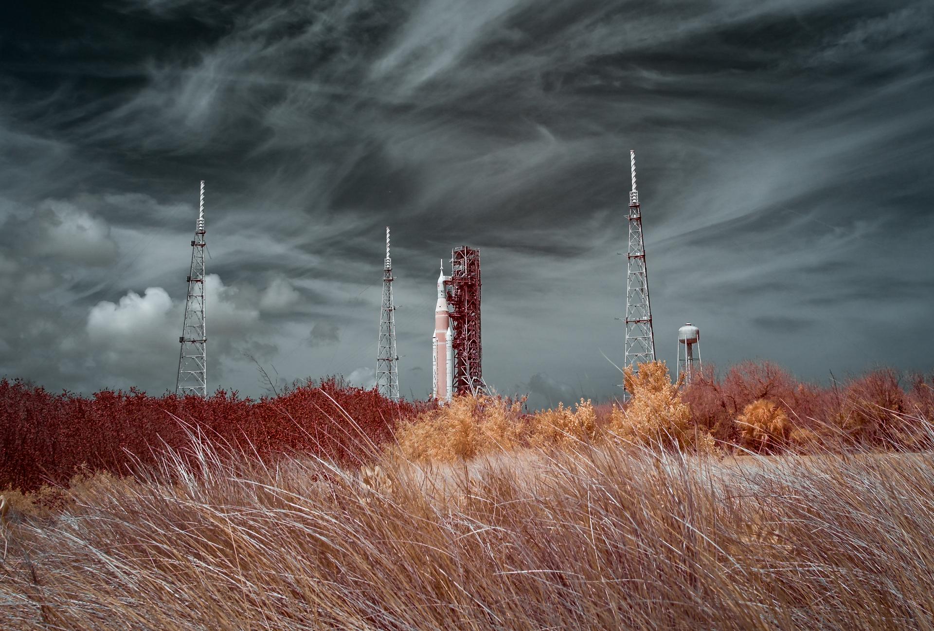NASA’s Artemis II Space Launch System (SLS) rocket and Orion spacecraft are seen in this false color infrared image, atop a mobile launcher at Launch Complex 39B, Tuesday, March 31, 2026, at NASA’s Kennedy Space Center in Florida. NASA’s Artemis II test flight will take Commander Reid Wiseman, Pilot Victor Glover, and Mission Specialist Christina Koch from NASA, and Mission Specialist Jeremy Hansen from the CSA (Canadian Space Agency), around the Moon and back to Earth with launch opportunities beginning in April 2026. Photo Credit: (NASA/Bill Ingalls)