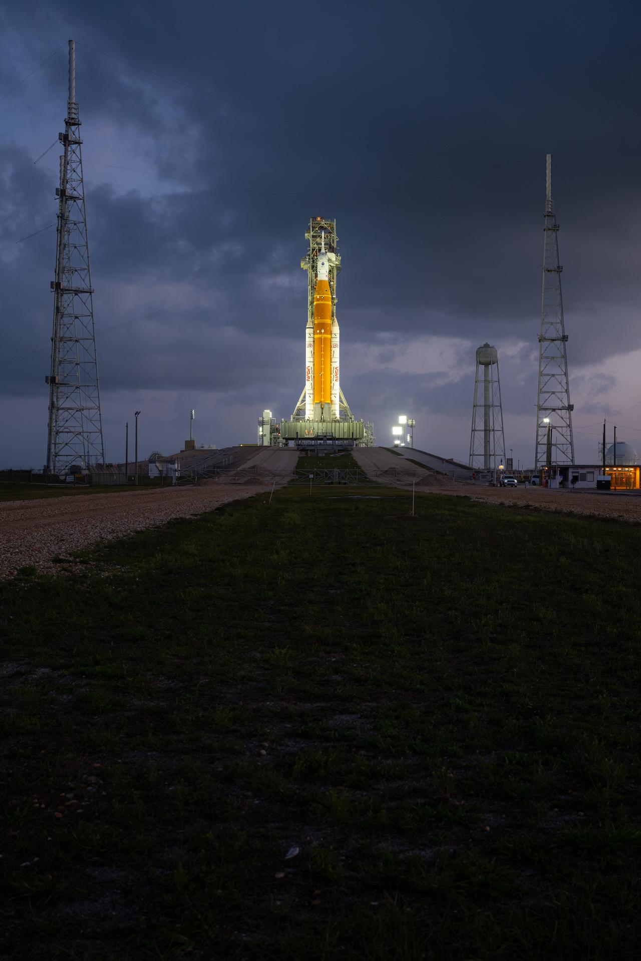NASA’s Artemis II Space Launch System (SLS) rocket and Orion spacecraft are seen standing atop a mobile launcher at Launch Complex 39B, Tuesday, March 31, 2026, at NASA’s Kennedy Space Center in Florida. NASA’s Artemis II test flight will take Commander Reid Wiseman, Pilot Victor Glover, and Mission Specialist Christina Koch from NASA, and Mission Specialist Jeremy Hansen from the CSA (Canadian Space Agency), around the Moon and back to Earth no earlier than April 1, 2026. Photo Credit: (NASA/John Kraus)