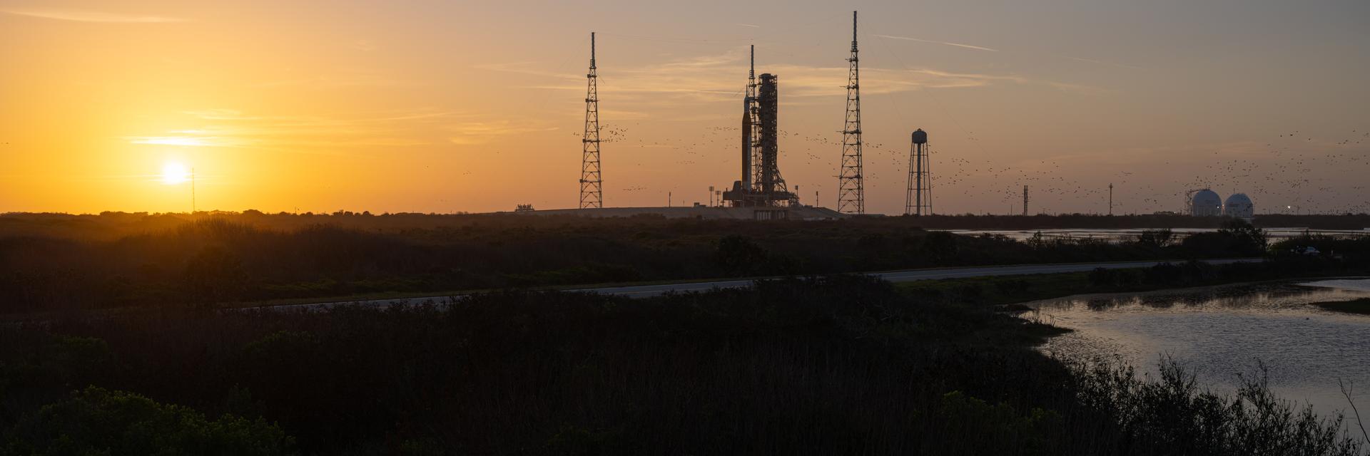 NASA’s Artemis II Space Launch System (SLS) rocket and Orion spacecraft are seen standing atop a mobile launcher at Launch Complex 39B, Tuesday, March 31, 2026, at NASA’s Kennedy Space Center in Florida. NASA’s Artemis II test flight will take Commander Reid Wiseman, Pilot Victor Glover, and Mission Specialist Christina Koch from NASA, and Mission Specialist Jeremy Hansen from the CSA (Canadian Space Agency), around the Moon and back to Earth no earlier than April 1, 2026. Photo Credit: (NASA/John Kraus)