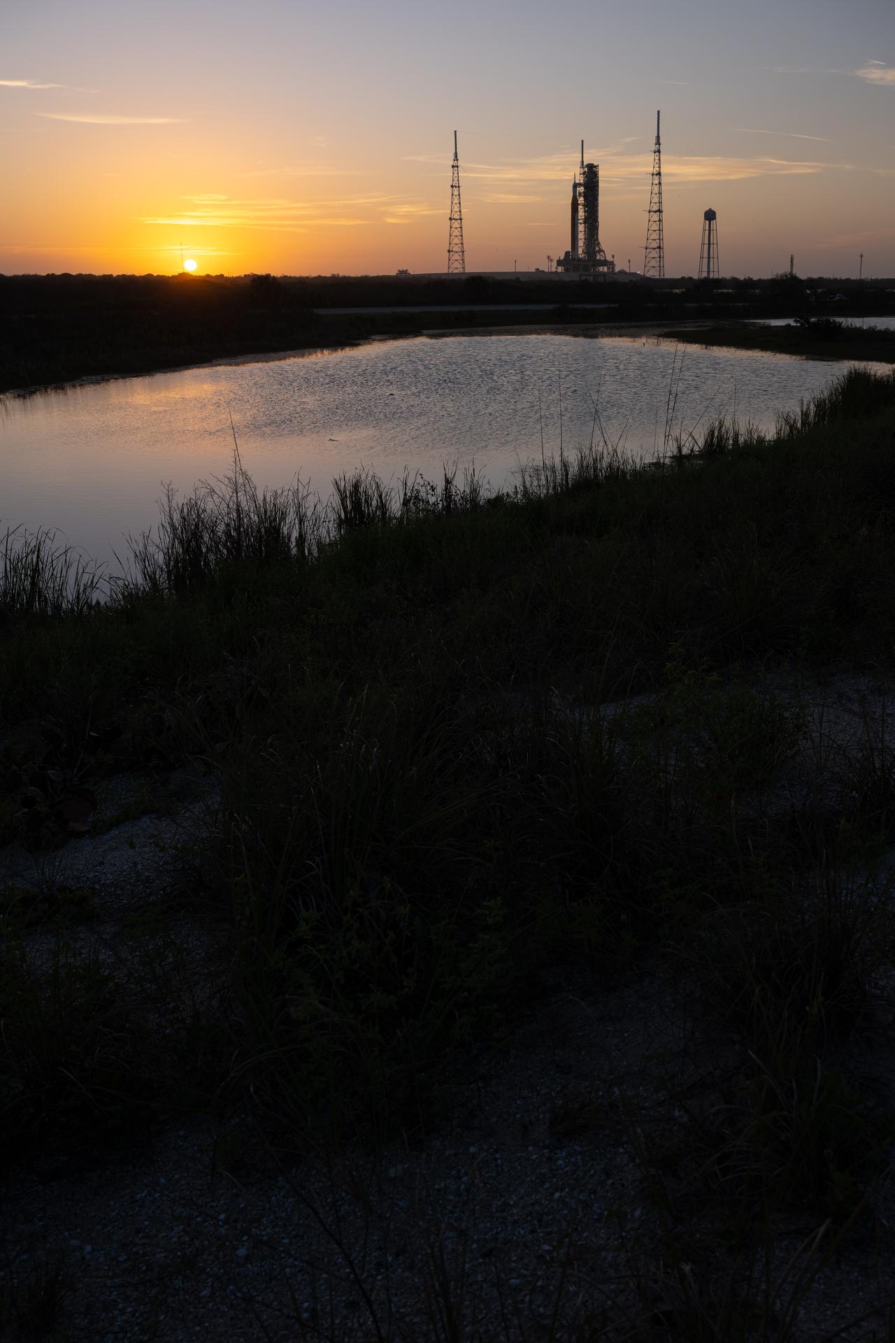 NASA’s Artemis II Space Launch System (SLS) rocket and Orion spacecraft are seen standing atop a mobile launcher at Launch Complex 39B, Tuesday, March 31, 2026, at NASA’s Kennedy Space Center in Florida. NASA’s Artemis II test flight will take Commander Reid Wiseman, Pilot Victor Glover, and Mission Specialist Christina Koch from NASA, and Mission Specialist Jeremy Hansen from the CSA (Canadian Space Agency), around the Moon and back to Earth no earlier than April 1, 2026. Photo Credit: (NASA/John Kraus)