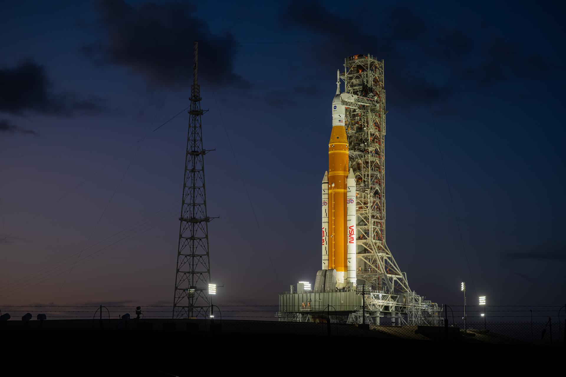 NASA’s Artemis II Space Launch System (SLS) rocket and Orion spacecraft are seen standing atop a mobile launcher at Launch Complex 39B, Tuesday, March 31, 2026, at NASA’s Kennedy Space Center in Florida. NASA’s Artemis II test flight will take Commander Reid Wiseman, Pilot Victor Glover, and Mission Specialist Christina Koch from NASA, and Mission Specialist Jeremy Hansen from the CSA (Canadian Space Agency), around the Moon and back to Earth no earlier than April 1, 2026. Photo Credit: (NASA/John Kraus)