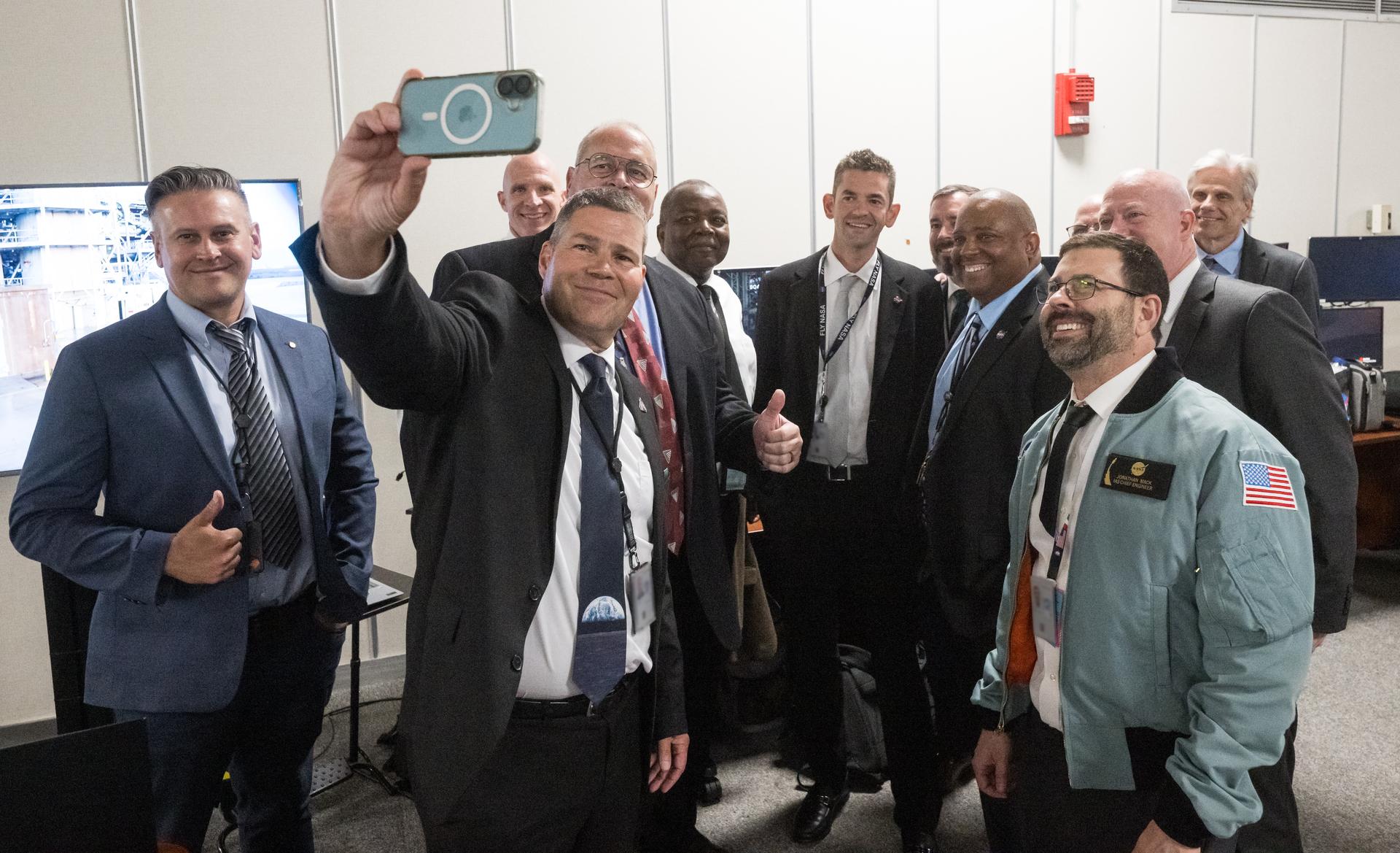 Artemis II mission teams pose for a selfie with NASA Administrator Jared Isaacman after  monitor the launch of NASA’s Space Launch System (SLS) rocket and Orion spacecraft with NASA astronauts Reid Wiseman, commander; Victor Glover, pilot; Christina Koch, mission specialist; and CSA (Canadian Space Agency) astronaut Jeremy Hansen, mission specialist onboard on the Artemis II mission in Firing Room 2 of the Rocco A. Petrone Launch Control Center, Wednesday, April 1, 2026, at NASA’s Kennedy Space Center in Florida. NASA’s Artemis II mission will take Wiseman, Glover, Koch, and Hansen on a 10-day journey around the Moon and back aboard SLS rocket and Orion spacecraft from Launch Complex 39B. The quartet launched at 6:35pm EDT. Photo Credit: (NASA/Aubrey Gemignani) NOTE - Portions of this image have been blurred for security reasons.