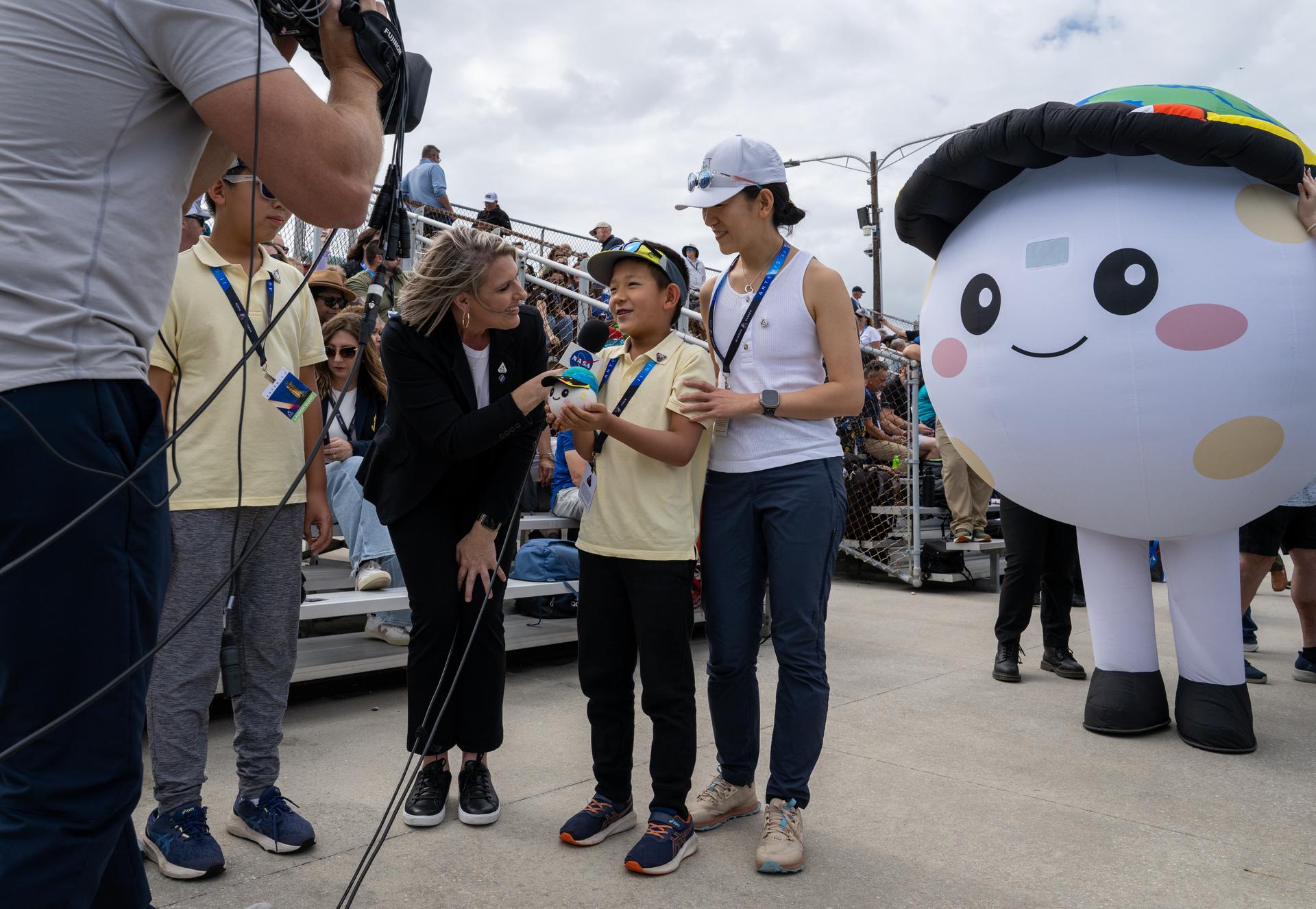 Lucas Ye, designer of zero gravity indicator “Rise,” participates in an interview with members of the NASA Broadcast team at the Banana Creek viewing site as the countdown progresses for the launch of NASA’s Space Launch System (SLS) rocket and Orion spacecraft with Commander Reid Wiseman, Pilot Victor Glover, and Mission Specialist Christina Koch from NASA, and Mission Specialist Jeremy Hansen from the CSA (Canadian Space Agency) on the Artemis II mission, Wednesday, April 1, 2026, at NASA’s Kennedy Space Center in Florida. NASA’s Artemis II mission will take Wiseman, Glover, Koch, and Hansen on a 10-day journey around the Moon and back aboard SLS rocket and Orion spacecraft from Launch Complex 39B with launch window opening at 6:24 p.m. EDT.  Photo Credit: (NASA/Keegan Barber)