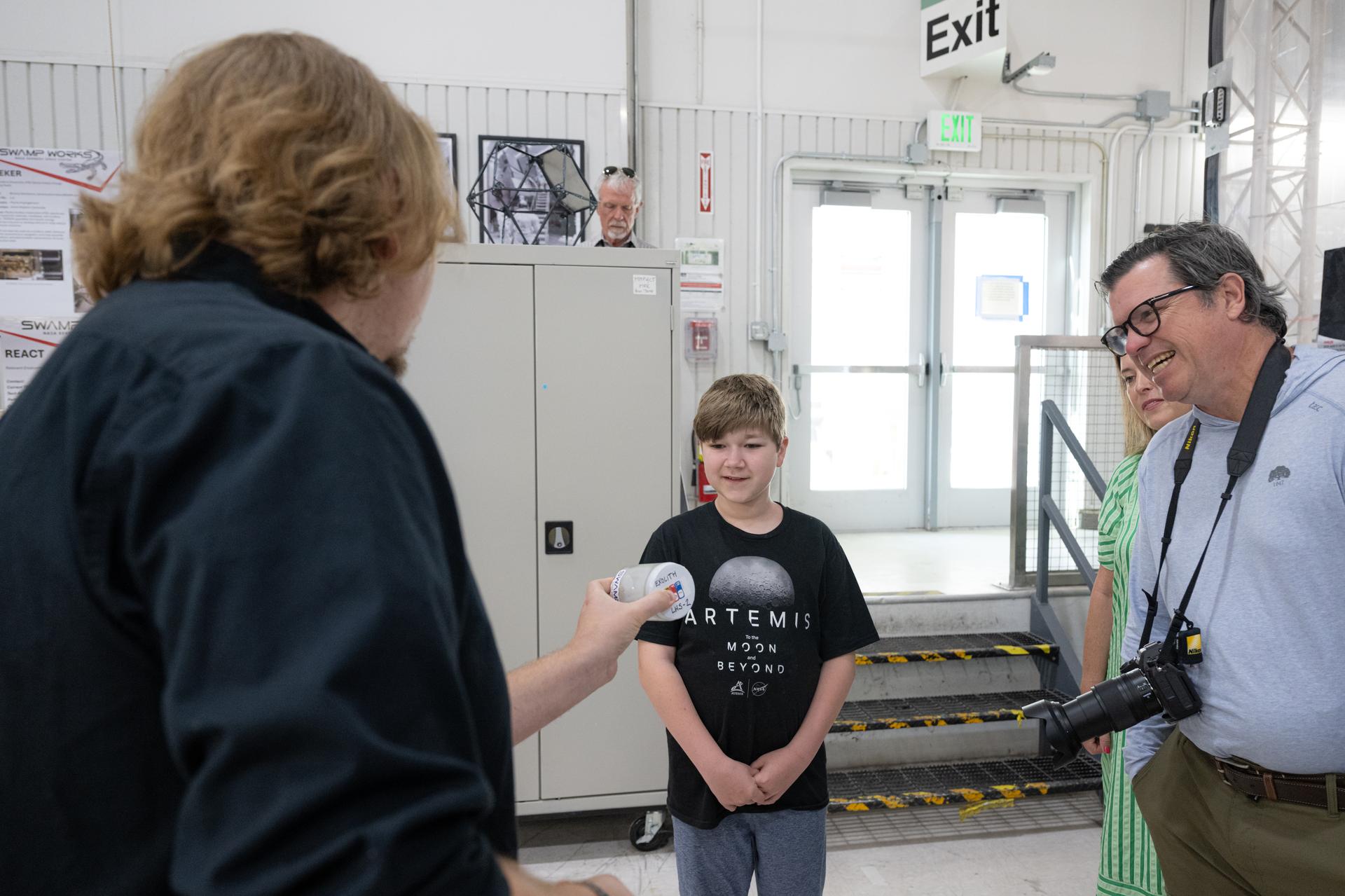 Eleven-year-old Hilt Boling, center, and parents Kent Boling and Rachel Boling, right, tour the SwampWorks facility, Friday, Apr. 3, 2026, at NASA’s Kennedy Space Center in Florida. When asked during an April 1 television appearance why he loved space and being at the Artemis II launch, Boling exclaimed: “We’re going back to the freaking Moon, that’s why!” His comments received widespread social media attention in the following days. Photo Credit: (NASA/John Kraus)