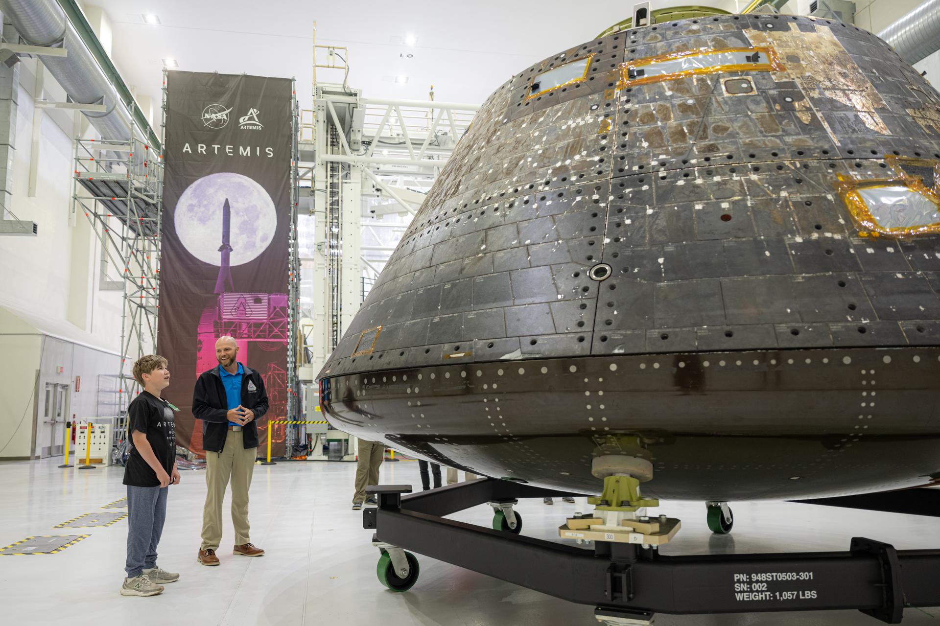 Eleven-year-old Hilt Boling, left, visits the Artemis I Orion spacecraft at the Neil A. Armstrong Operations and Checkout Building, Friday, Apr. 3, 2026, at NASA’s Kennedy Space Center in Florida. When asked during an April 1 television appearance why he loved space and being at the Artemis II launch, Boling exclaimed: “We’re going back to the freaking Moon, that’s why!” His comments received widespread social media attention in the following days. Photo Credit: (NASA/John Kraus)