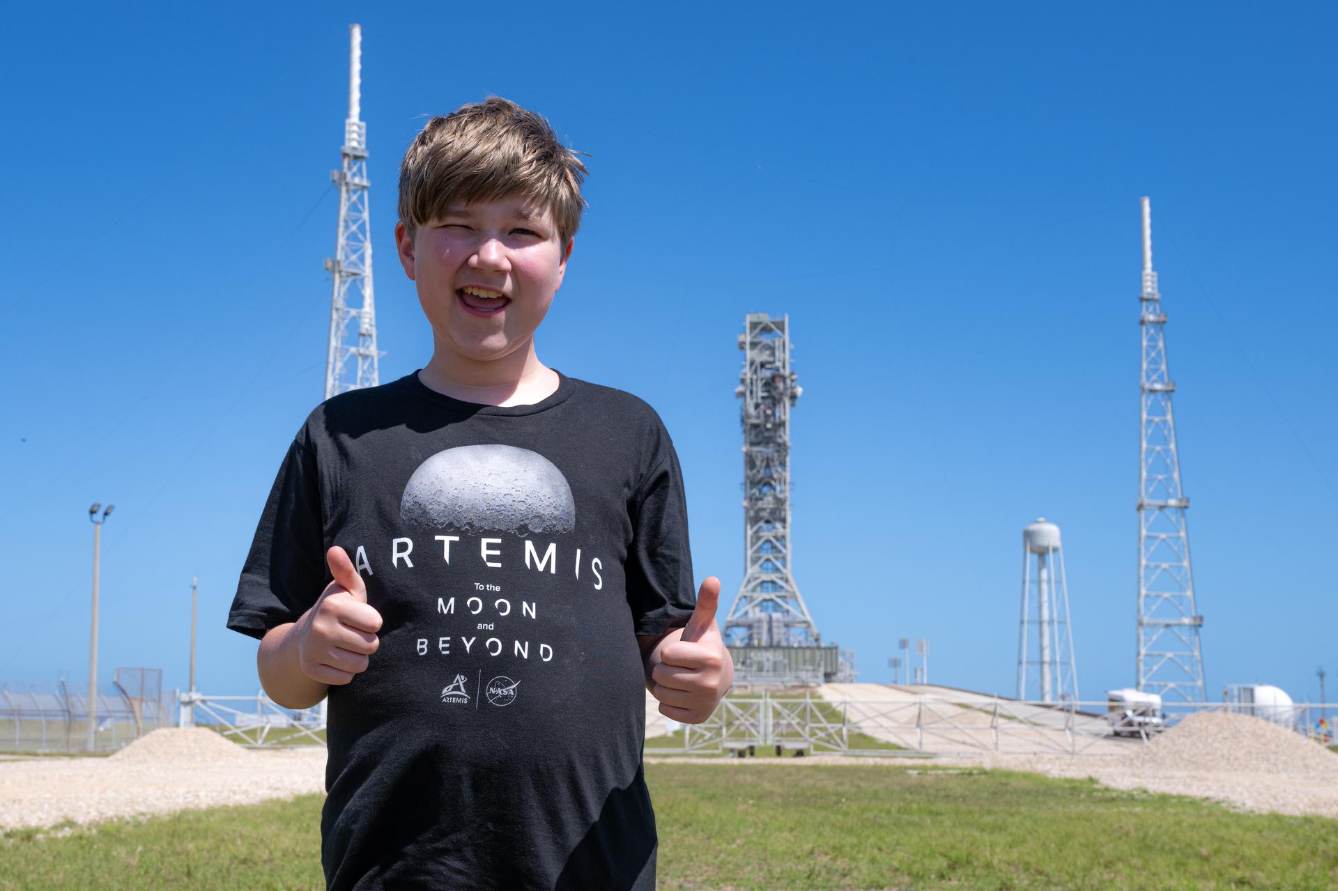 Eleven-year-old Hilt Boling poses for a photograph near Launch Complex 39B, Friday, Apr. 3, 2026, at NASA’s Kennedy Space Center in Florida. When asked during an April 1 television appearance why he loved space and being at the Artemis II launch, Boling exclaimed: “We’re going back to the freaking Moon, that’s why!” His comments received widespread social media attention in the following days. Photo Credit: (NASA/John Kraus)