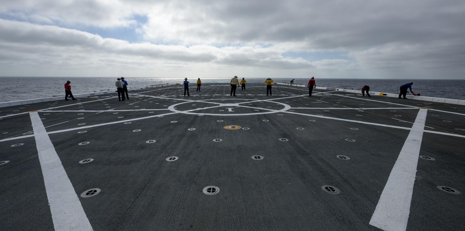 U.S. Navy sailors inspect the flight deck on USS John P. Murtha (LPD 26) as NASA, U.S. Navy, and U.S. Air Force teams head into the Pacific Ocean for the return of the Artemis II crewmembers to Earth, Monday, April 6, 2026, in the Pacific Ocean off the coast of California. NASA’s Artemis II mission is taking NASA astronauts Reid Wiseman, commander; Victor Glover, pilot; Christina Koch, mission specialist; and CSA (Canadian Space Agency) astronaut Jeremy Hansen, mission specialist on a 10-day journey around the Moon and back aboard their Orion spacecraft. Wiseman, Glover, Koch, and Hansen are scheduled to splash down off the coast of San Diego at approximately 5:07 p.m. PDT (8:07 p.m. EDT) on Friday, April 10.  Photo Credit: (NASA/Bill Ingalls)