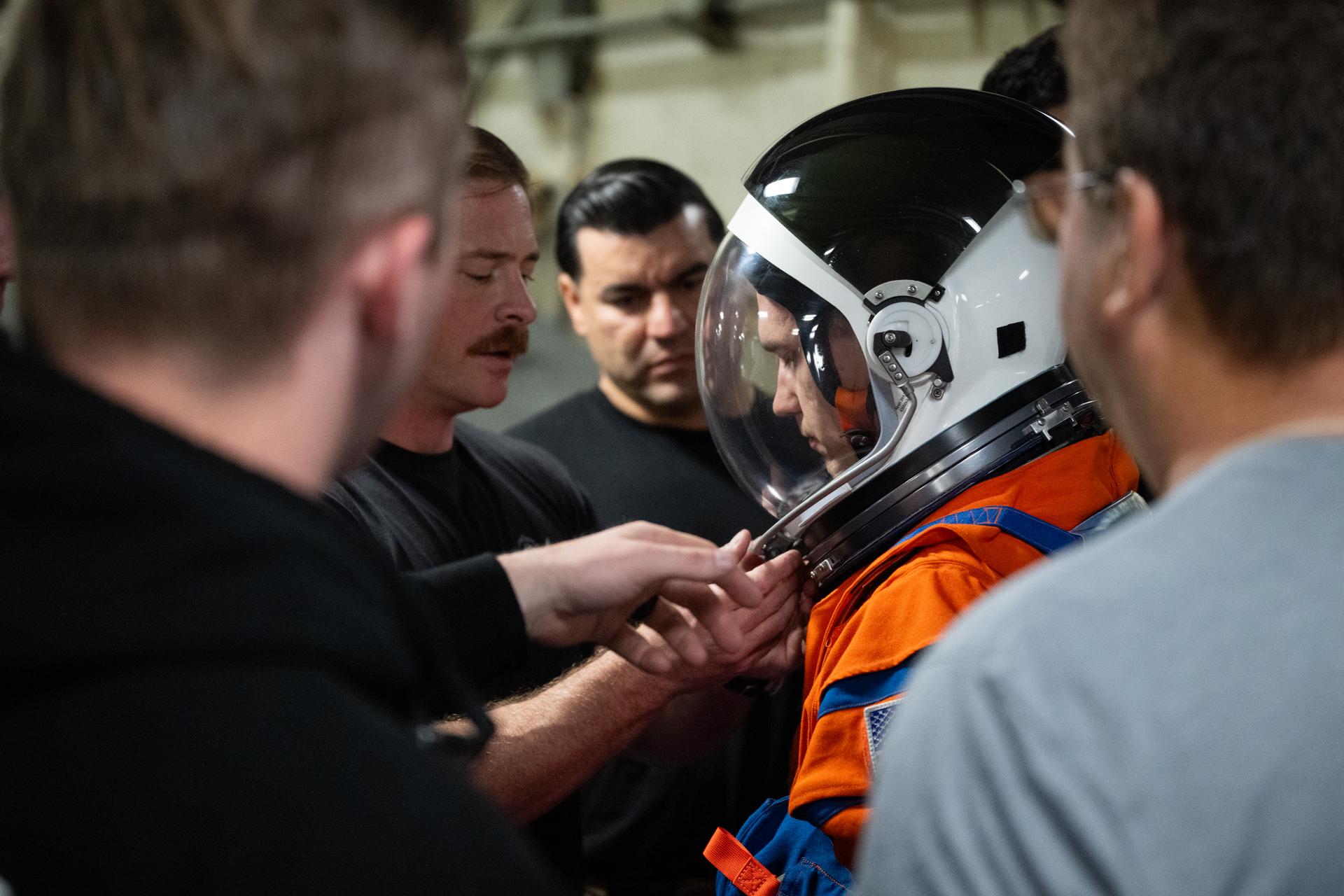 Nicholas Houghton, an Orion Crew Survival System engineer at NASA’s Johnson Space Center, wearing an Orion Crew Survival System suit, conducts familiarization training with U.S. Navy divers on doffing the suit onboard USS John P. Murtha ahead of the return of the Artemis II crewmembers to Earth, Tuesday, April 7, 2026, in the Pacific Ocean off the coast of California. NASA’s Artemis II mission is taking NASA astronauts Reid Wiseman, commander; Victor Glover, pilot; Christina Koch, mission specialist; and CSA (Canadian Space Agency) astronaut Jeremy Hansen, mission specialist on a 10-day journey around the Moon and back aboard their Orion spacecraft. Wiseman, Glover, Koch, and Hansen are scheduled to splash down off the coast of San Diego at approximately 5:07 p.m. PDT (8:07 p.m. EDT) on Friday, April 10.  Photo Credit: (NASA/Joel Kowsky)