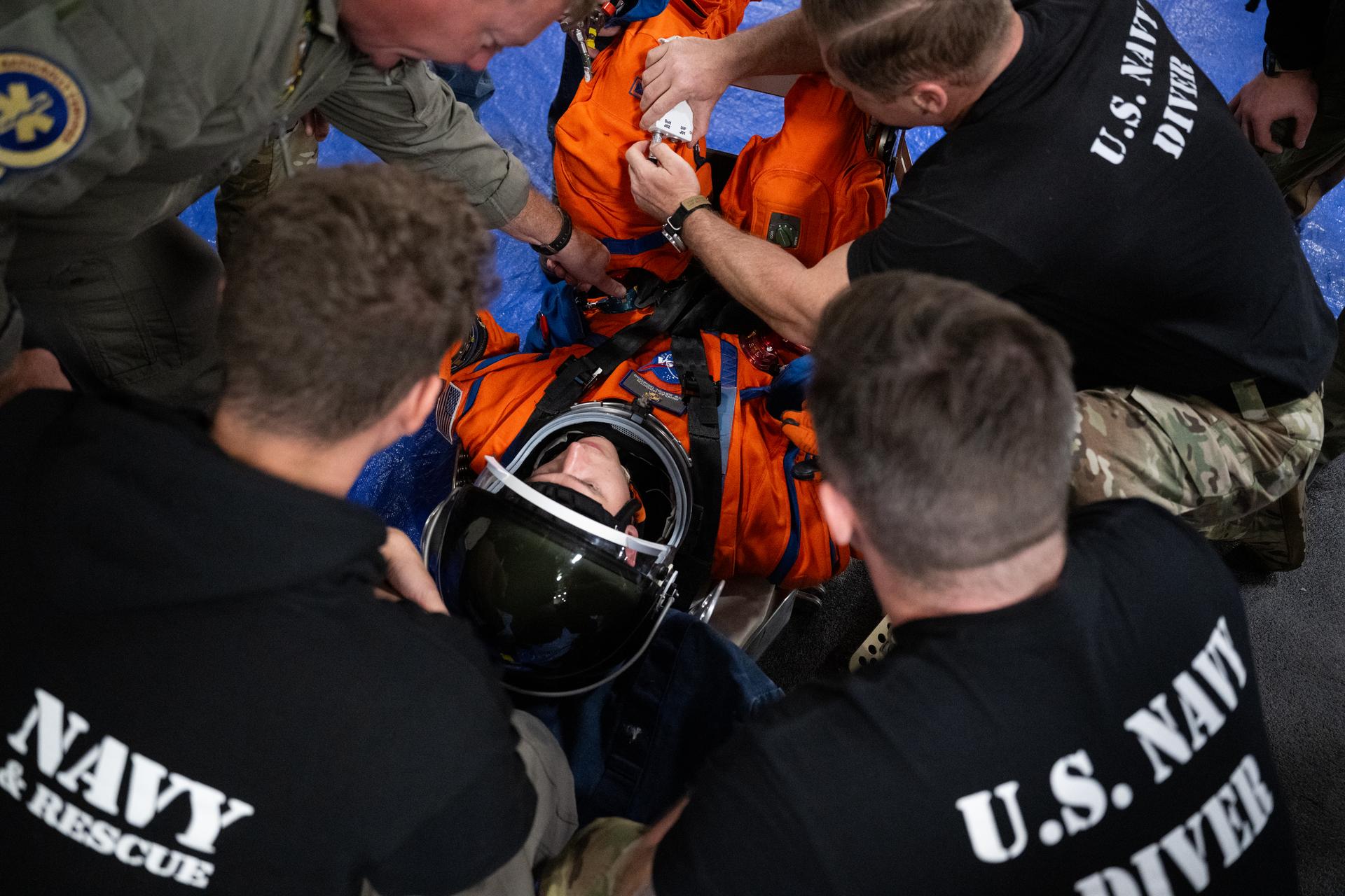 Nicholas Houghton, an Orion Crew Survival System engineer at NASA’s Johnson Space Center, wearing an Orion Crew Survival System suit, conducts familiarization training with U.S. Navy divers on doffing the suit onboard USS John P. Murtha ahead of the return of the Artemis II crewmembers to Earth, Tuesday, April 7, 2026, in the Pacific Ocean off the coast of California. NASA’s Artemis II mission is taking NASA astronauts Reid Wiseman, commander; Victor Glover, pilot; Christina Koch, mission specialist; and CSA (Canadian Space Agency) astronaut Jeremy Hansen, mission specialist on a 10-day journey around the Moon and back aboard their Orion spacecraft. Wiseman, Glover, Koch, and Hansen are scheduled to splash down off the coast of San Diego at approximately 5:07 p.m. PDT (8:07 p.m. EDT) on Friday, April 10.  Photo Credit: (NASA/Joel Kowsky)