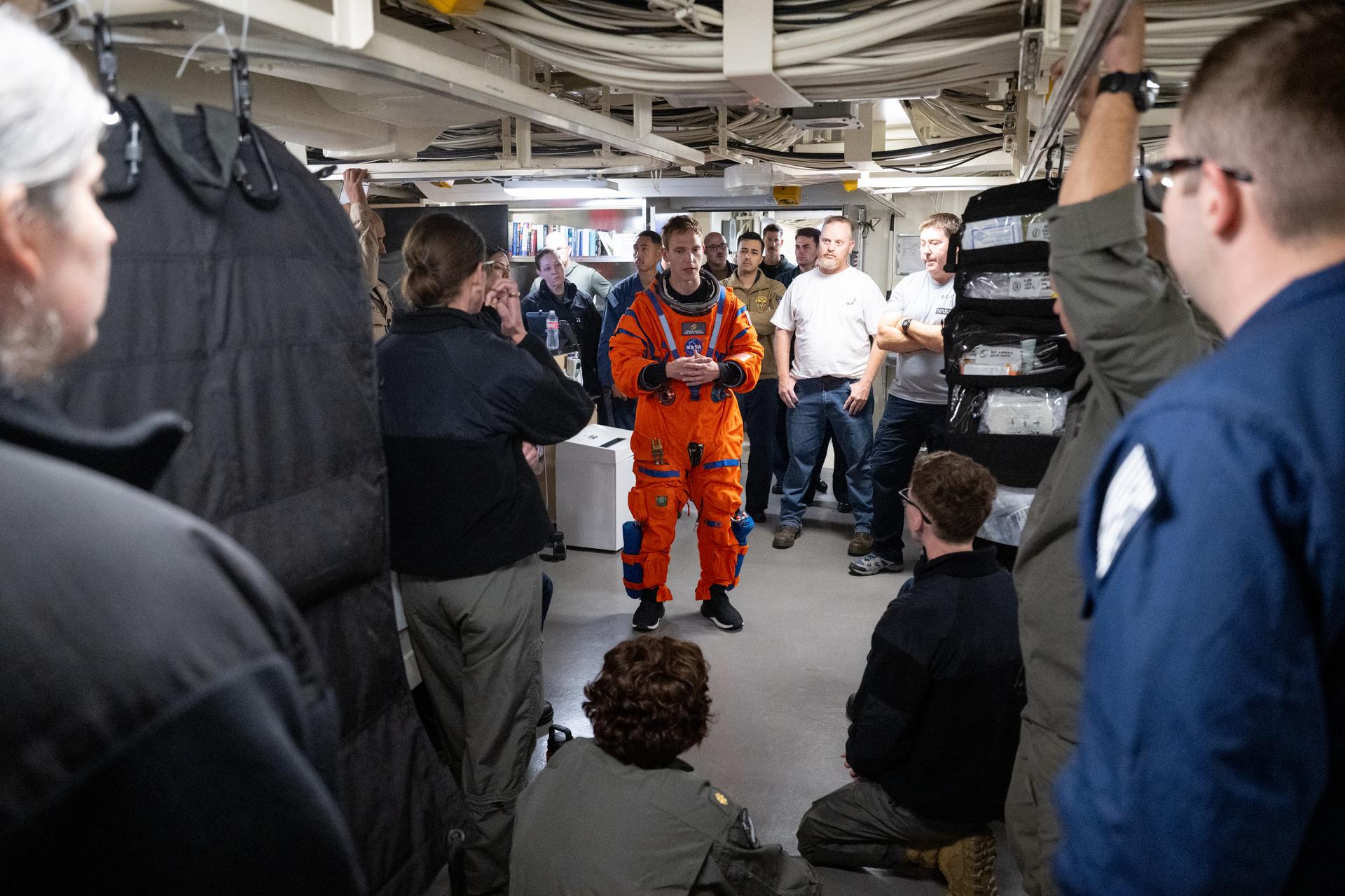 Nicholas Houghton, an Orion Crew Survival System engineer at NASA’s Johnson Space Center, wears an Orion Crew Survival System suit as he conducts familiarization training with U.S. Navy medical personnel on doffing the suit onboard USS John P. Murtha ahead of the return of the Artemis II crewmembers to Earth, Tuesday, April 7, 2026, in the Pacific Ocean off the coast of California. NASA’s Artemis II mission is taking NASA astronauts Reid Wiseman, commander; Victor Glover, pilot; Christina Koch, mission specialist; and CSA (Canadian Space Agency) astronaut Jeremy Hansen, mission specialist on a 10-day journey around the Moon and back aboard their Orion spacecraft. Wiseman, Glover, Koch, and Hansen are scheduled to splash down off the coast of San Diego at approximately 5:07 p.m. PDT (8:07 p.m. EDT) on Friday, April 10.  Photo Credit: (NASA/Joel Kowsky)