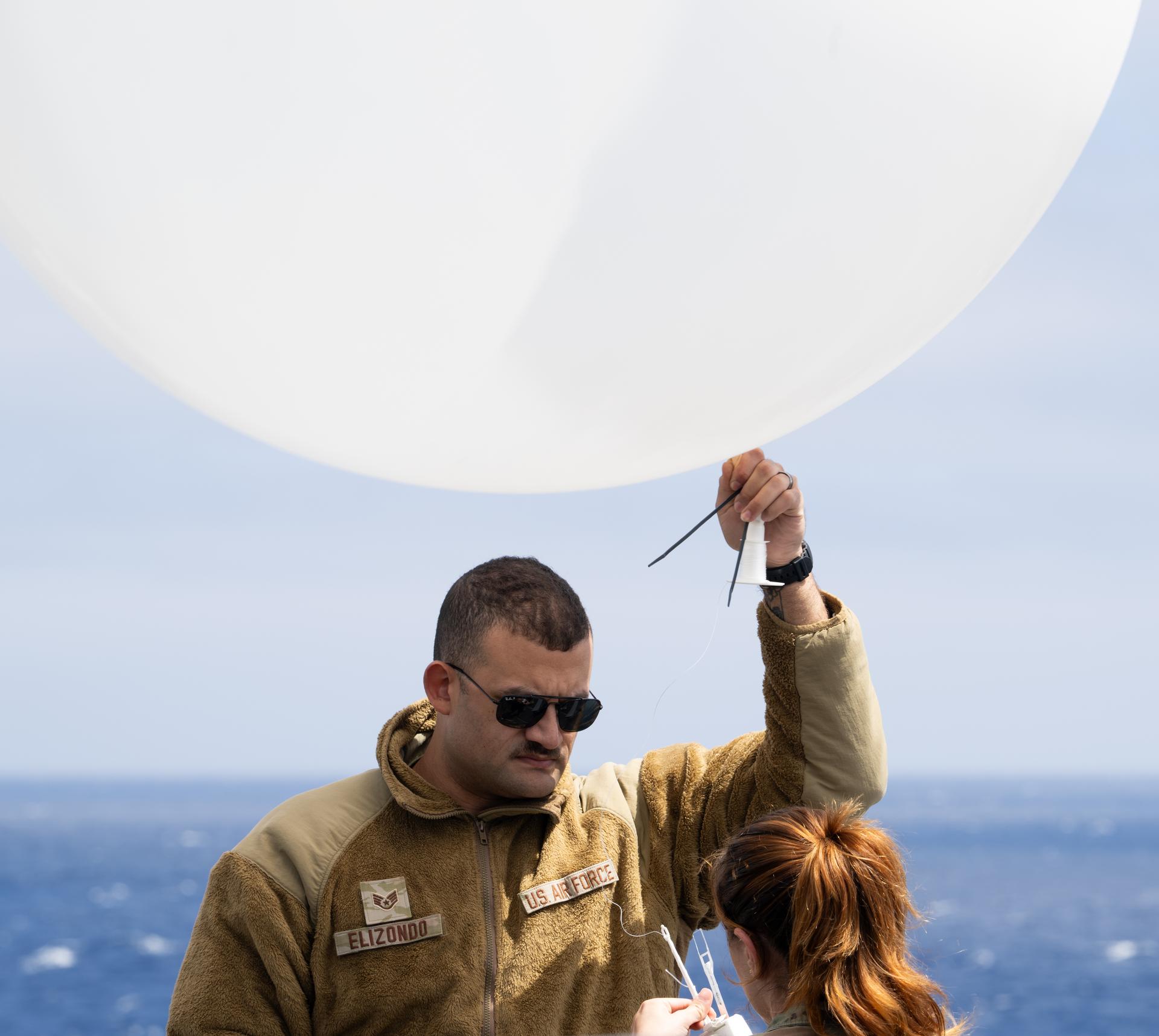 Airmen of the 45th Weather Squadron prepare a weather balloon for launch as NASA, U.S. Navy, and U.S. Air Force teams continue to prepare for the the return of the Artemis II crewmembers to Earth, Wednesday, April 8, 2026, onboard USS John P. Murtha in the Pacific Ocean off the coast of California. NASA’s Artemis II mission is taking NASA astronauts Reid Wiseman, commander; Victor Glover, pilot; Christina Koch, mission specialist; and CSA (Canadian Space Agency) astronaut Jeremy Hansen, mission specialist on a 10-day journey around the Moon and back aboard their Orion spacecraft. Wiseman, Glover, Koch, and Hansen are scheduled to splash down off the coast of San Diego at approximately 5:07 p.m. PDT (8:07 p.m. EDT) on Friday, April 10.  Photo Credit: (NASA/Joel Kowsky)