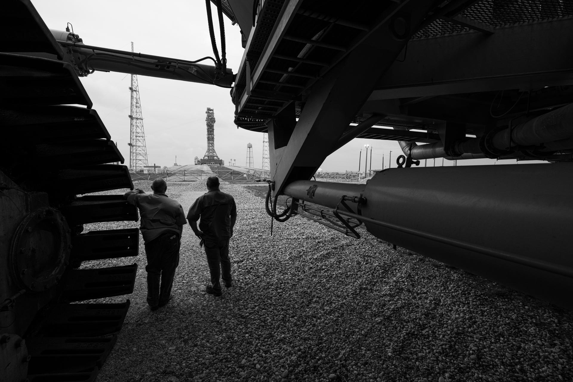Clark Ford, element operations manager at NASA's Kennedy Space Center, left, and Doug Levine, contractor security manager at NASA's Kennedy Space Center, right, pose for a photograph with Crawler Transporter 2 outside the gate of Launch Complex 39B, Wednesday, Apr. 8, 2026, at NASA’s Kennedy Space Center in Florida. Photo Credit: (NASA/John Kraus)