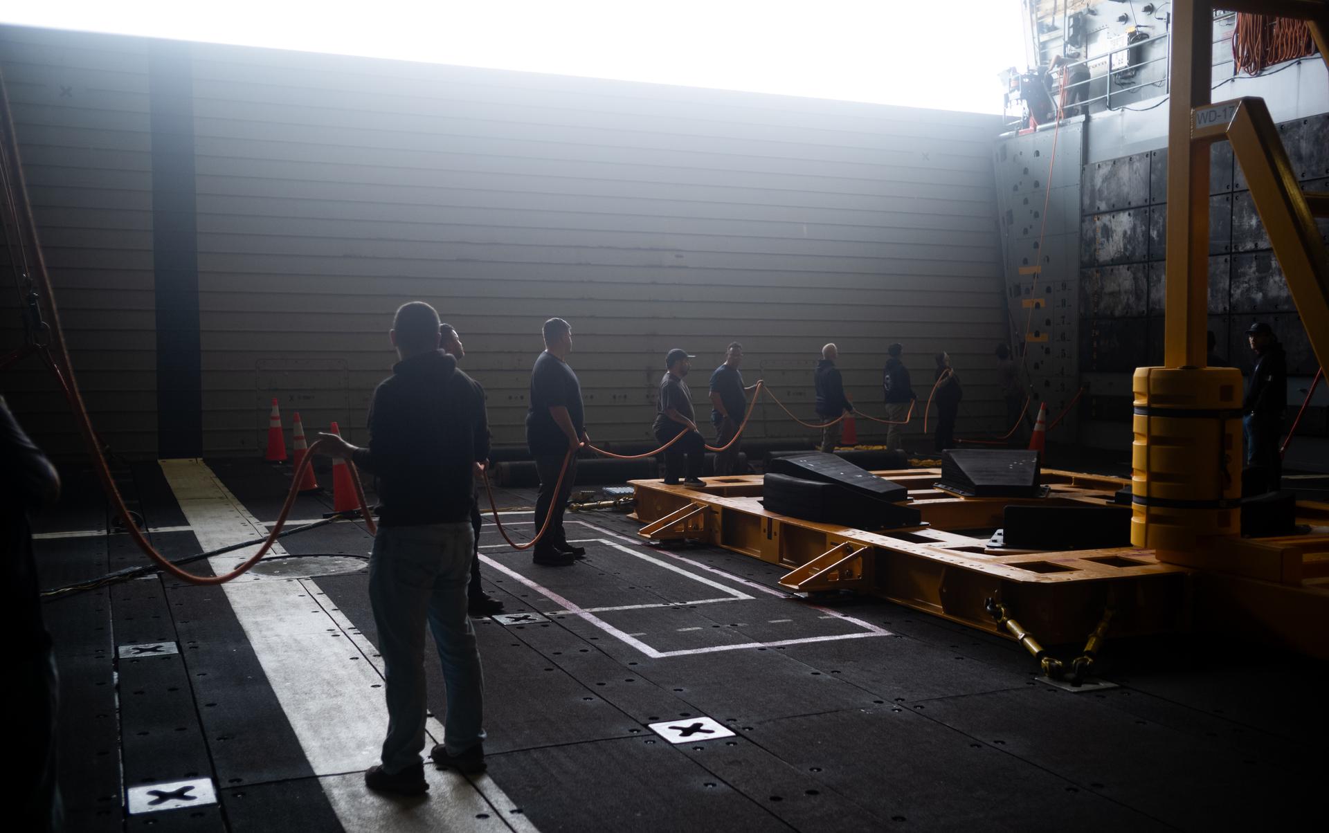 NASA Landing and Recovery team members prepare the well deck of USS John P. Murtha for the return of the agency’s Orion spacecraft and Artemis II crewmembers to Earth, Thursday, April 9, 2026, in the Pacific Ocean off the coast of California. NASA’s Artemis II mission is taking NASA astronauts Reid Wiseman, commander; Victor Glover, pilot; Christina Koch, mission specialist; and CSA (Canadian Space Agency) astronaut Jeremy Hansen, mission specialist on a 10-day journey around the Moon and back aboard their Orion spacecraft. Wiseman, Glover, Koch, and Hansen are scheduled to splash down off the coast of San Diego at approximately 5:07 p.m. PDT (8:07 p.m. EDT) on Friday, April 10.  Photo Credit: (NASA/Joel Kowsky)