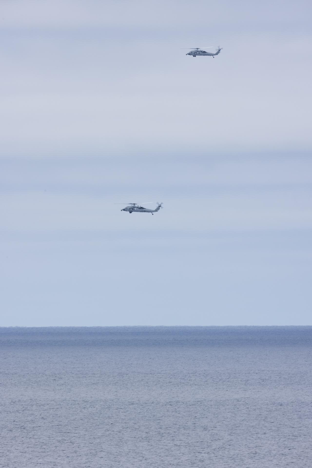 Two U.S. Navy MH-60 Seahawks from Helicopter Sea Combat Squadron (HSC) 23 are seen from aboard USS John P. Murtha as NASA, U.S. Navy., and U.S. Air Force teams prepare for the the return of the Artemis II crewmembers to Earth, Friday, April 10, 2026, in the Pacific Ocean off the coast of California. NASA’s Artemis II mission is taking NASA astronauts Reid Wiseman, commander; Victor Glover, pilot; Christina Koch, mission specialist; and CSA (Canadian Space Agency) astronaut Jeremy Hansen, mission specialist on a 10-day journey around the Moon and back aboard their Orion spacecraft. Wiseman, Glover, Koch, and Hansen are scheduled to splash down off the coast of San Diego at approximately 5:07 p.m. PDT (8:07 p.m. EDT).  Photo Credit: (NASA/Joel Kowsky)