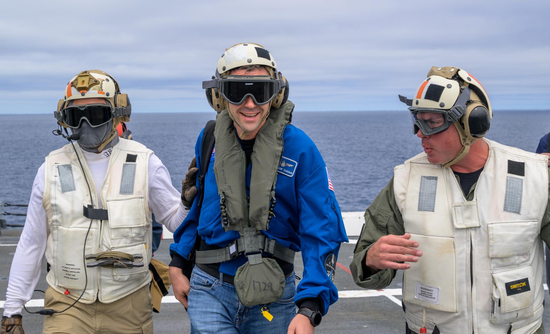 NASA Administrator Jared Isaacman, center, is greeted by Capt. Erik Kenny, commanding officer, USS John P. Murtha (LPD), right, after Isaacman arrived on a U.S. Navy CMV-22 Osprey with Michael Altenhofen, senior advisor to the NASA Administrator, U.S. Navy Rear Adm. Brent DeVore, Commander, Expeditionary Strike Group Three, Michael Altenhofen, senior advisor to the NASA Administrator, and U.S. Air Force Maj. Gen. Michael A. Valle, Deputy Commander, First Air Force, as NASA and U.S. military teams prepare for the the return of the Artemis II crew members to Earth, Friday, April 10, 2026, in the Pacific Ocean off the coast of California. NASA’s Artemis II mission is taking NASA astronauts Reid Wiseman, commander; Victor Glover, pilot; Christina Koch, mission specialist; and CSA (Canadian Space Agency) astronaut Jeremy Hansen, mission specialist on a 10-day journey around the Moon and back aboard their Orion spacecraft. Wiseman, Glover, Koch, and Hansen are scheduled to splash down off the coast of San Diego at approximately 5:07 p.m. PDT (8:07 p.m. EDT). Photo Credit: (NASA/Bill Ingalls)
