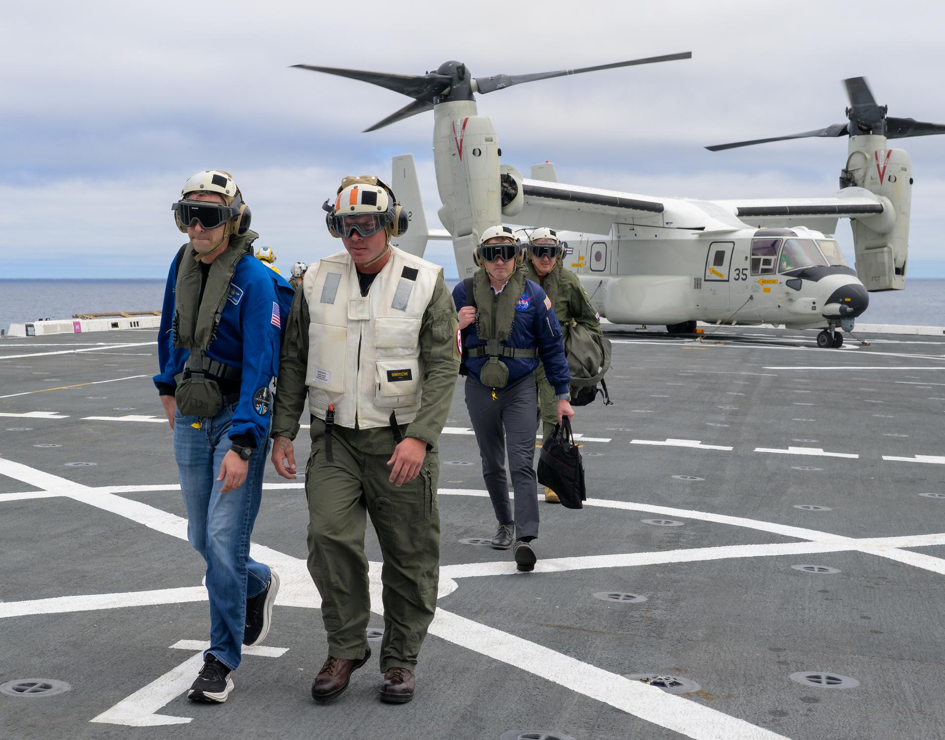 NASA Administrator Jared Isaacman, left, is greeted by Capt. Erik Kenny, commanding officer, USS John P. Murtha (LPD), right, after Isaacman arrived on a U.S. Navy CMV-22 Osprey with Michael Altenhofen, senior advisor to the NASA Administrator, U.S. Navy Rear Adm. Brent DeVore, Commander, Expeditionary Strike Group Three, Michael Altenhofen, senior advisor to the NASA Administrator, and U.S. Air Force Maj. Gen. Michael A. Valle, Deputy Commander, First Air Force, as NASA and U.S. military teams prepare for the the return of the Artemis II crew members to Earth, Friday, April 10, 2026, in the Pacific Ocean off the coast of California. NASA’s Artemis II mission is taking NASA astronauts Reid Wiseman, commander; Victor Glover, pilot; Christina Koch, mission specialist; and CSA (Canadian Space Agency) astronaut Jeremy Hansen, mission specialist on a 10-day journey around the Moon and back aboard their Orion spacecraft. Wiseman, Glover, Koch, and Hansen are scheduled to splash down off the coast of San Diego at approximately 5:07 p.m. PDT (8:07 p.m. EDT). Photo Credit: (NASA/Bill Ingalls)