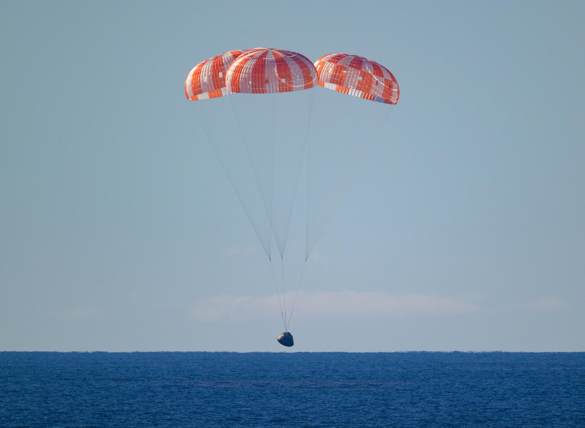 NASA’s Orion spacecraft with Artemis II crewmembers NASA astronauts Reid Wiseman, commander; Victor Glover, pilot; Christina Koch, mission specialist; and CSA (Canadian Space Agency) astronaut Jeremy Hansen, mission specialist aboard is seen under parachutes as it lands in the Pacific Ocean off the coast of California, Friday, April 10, 2026. NASA’s Artemis II mission took Wiseman, Glover, Koch, and Hansen on a nearly 10-day journey around the Moon and back to Earth. Following a splashdown at 8:07 p.m. EDT, NASA, U.S. Navy, and U.S. Air Force teams are working to bring the crewmembers and Orion spacecraft aboard USS John P. Murtha.  Photo Credit: (NASA/Bill Ingalls)