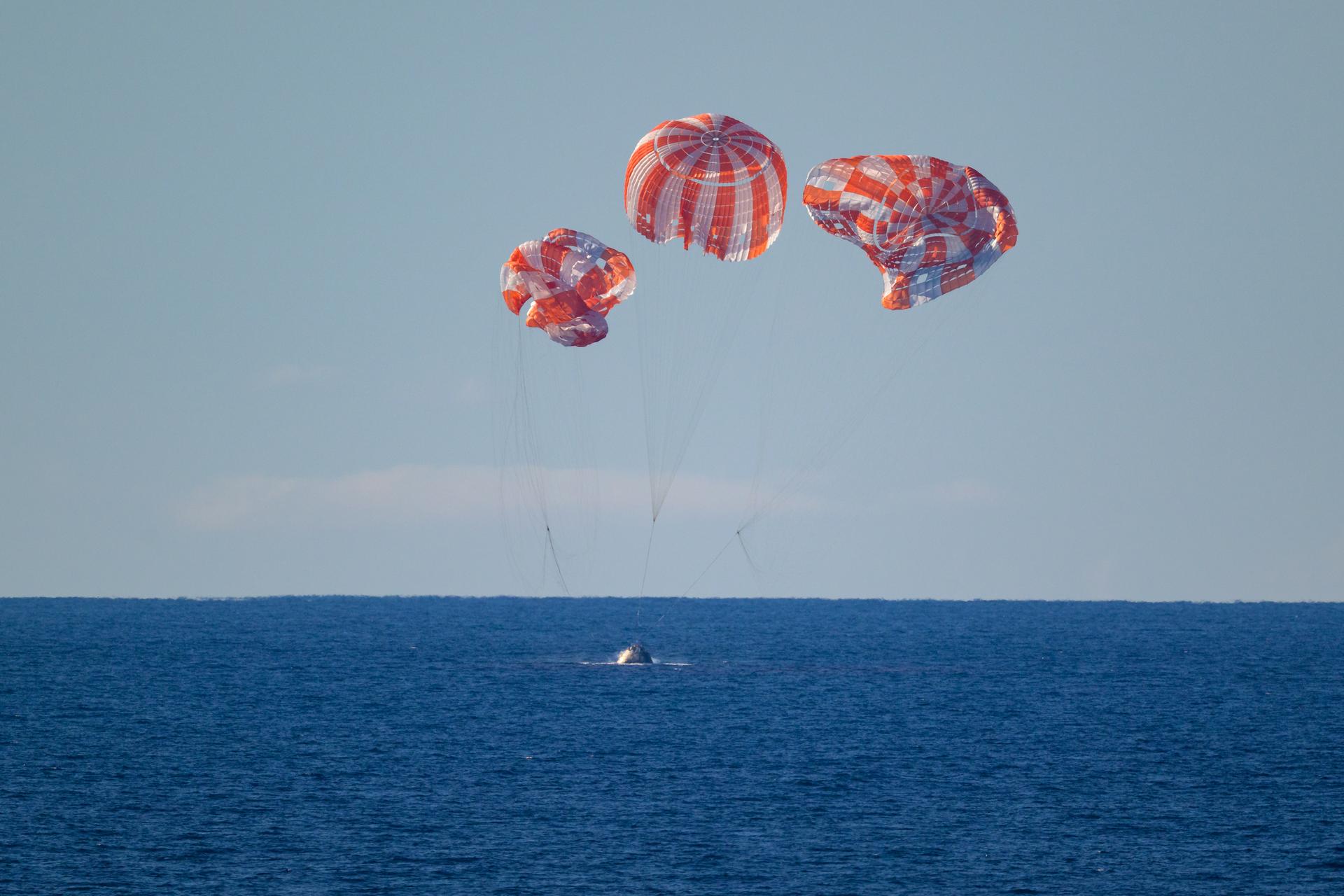 NASA’s Orion spacecraft with Artemis II crewmembers NASA astronauts Reid Wiseman, commander; Victor Glover, pilot; Christina Koch, mission specialist; and CSA (Canadian Space Agency) astronaut Jeremy Hansen, mission specialist aboard is seen as it lands in the Pacific Ocean off the coast of California, Friday, April 10, 2026. NASA’s Artemis II mission took Wiseman, Glover, Koch, and Hansen on a nearly 10-day journey around the Moon and back to Earth. Following a splashdown at 8:07p.m. EDT, NASA, U.S. Navy, and U.S. Air Force teams are working to bring the crewmembers and Orion spacecraft aboard USS John P. Murtha.  Photo Credit: (NASA/Bill Ingalls)