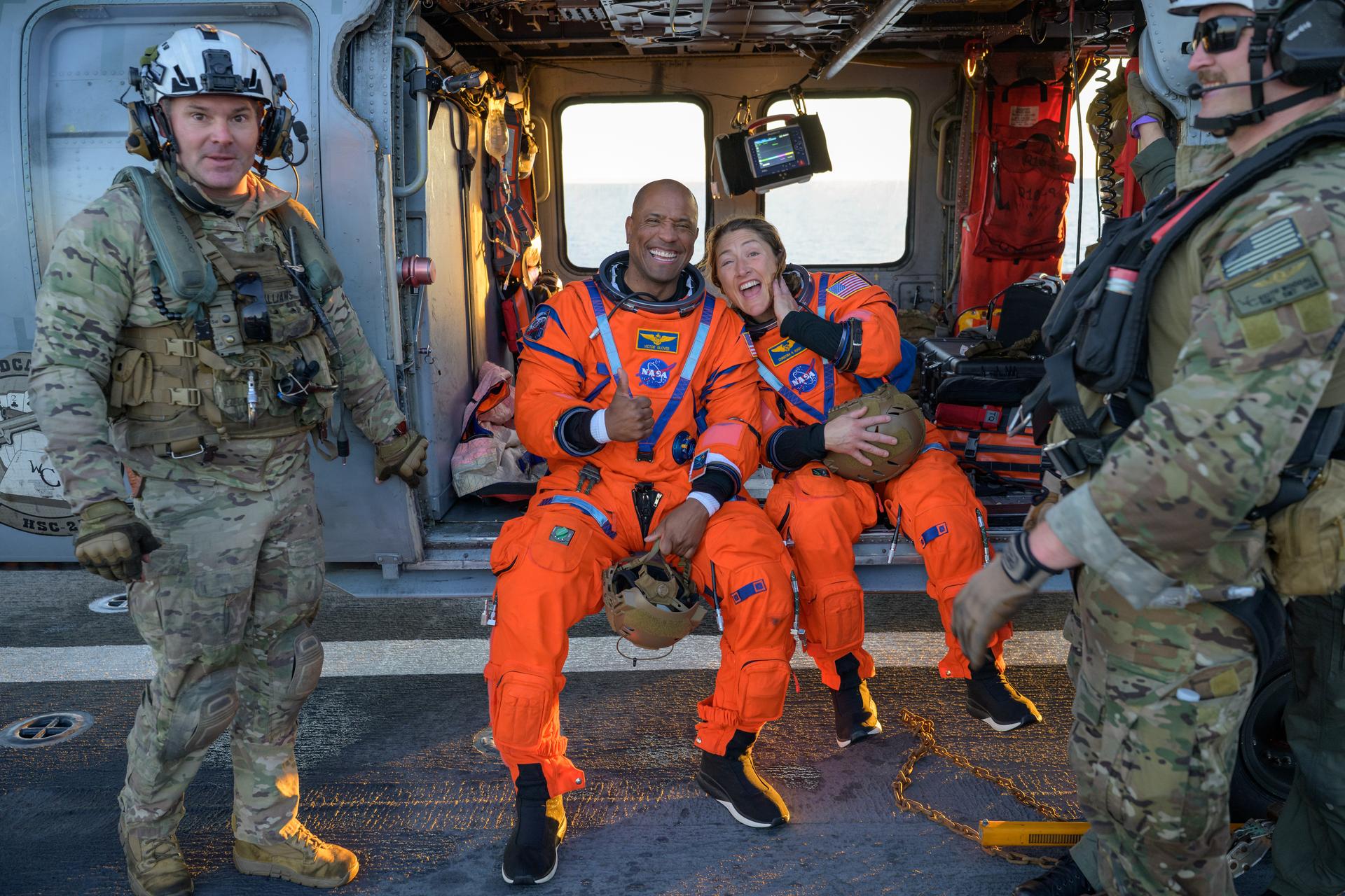 NASA astronaut Victor Glover, Artemis II pilot, left, and NASA astronaut Christina Koch, Artemis II mission specialist are seen sitting on a Navy MH-60 Seahawk from Helicopter Sea Combat Squadron (HSC) 23 on the flight deck of USS John P. Murtha after they and fellow crewmates CSA (Canadian Space Agency) astronaut Jeremy Hansen, Artemis II mission specialist, and NASA astronaut Reid Wiseman, Artemis II commander, were extracted from their Orion spacecraft after splashdown, Friday, April 10, 2026, in the Pacific Ocean off the coast of California. NASA’s Artemis II mission took the quartet on a nearly 10-day journey around the Moon and back to Earth. Following a splashdown at 5:07 p.m. PDT (8:07 p.m. EDT), NASA, U.S. Navy, and U.S. Air Force teams are working to bring the Orion spacecraft aboard the recovery ship. Photo Credit: (NASA/Bill Ingalls)